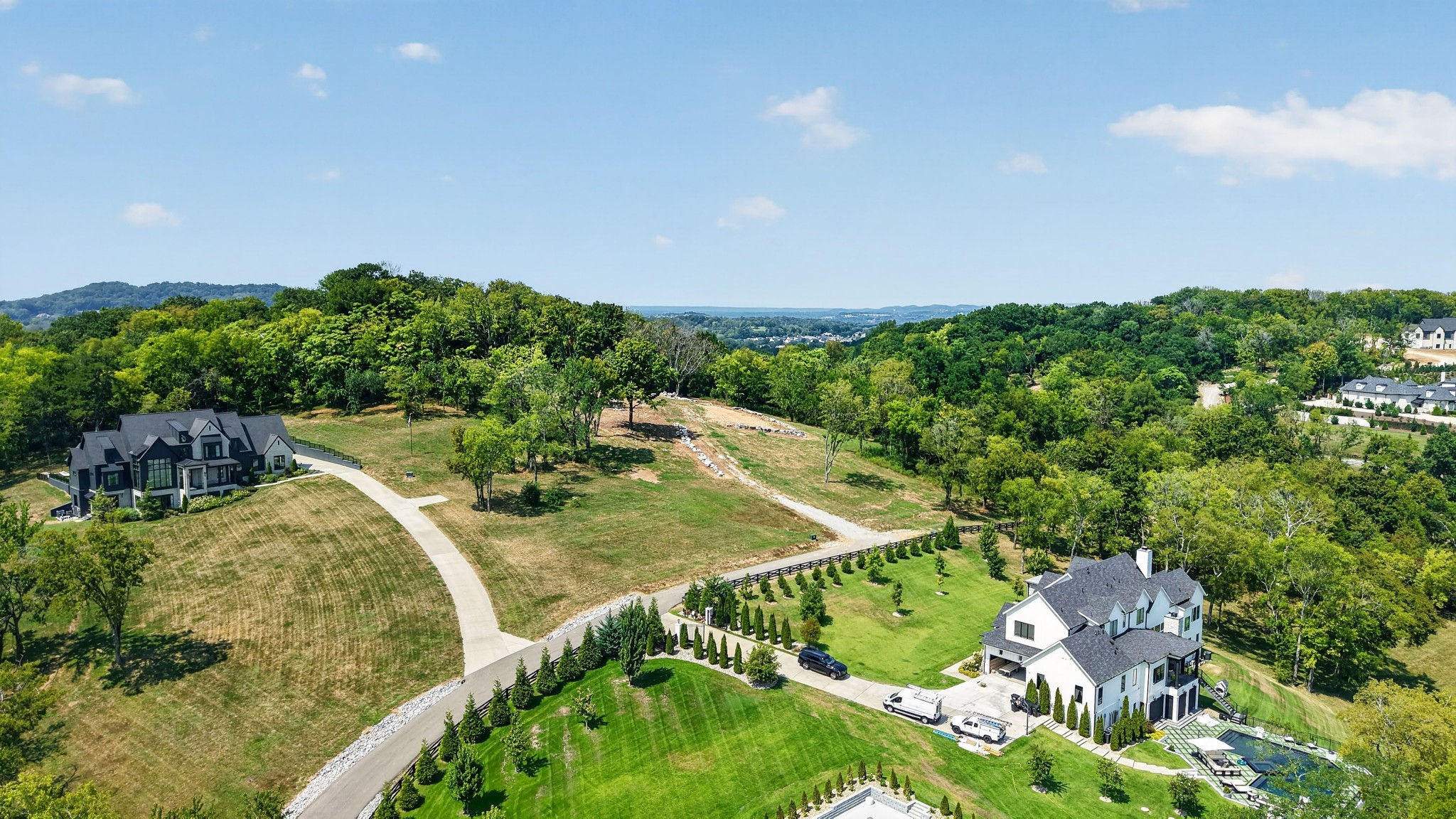 Aerial view of an open Franklin lot between homes, with wooded hills in the distance.