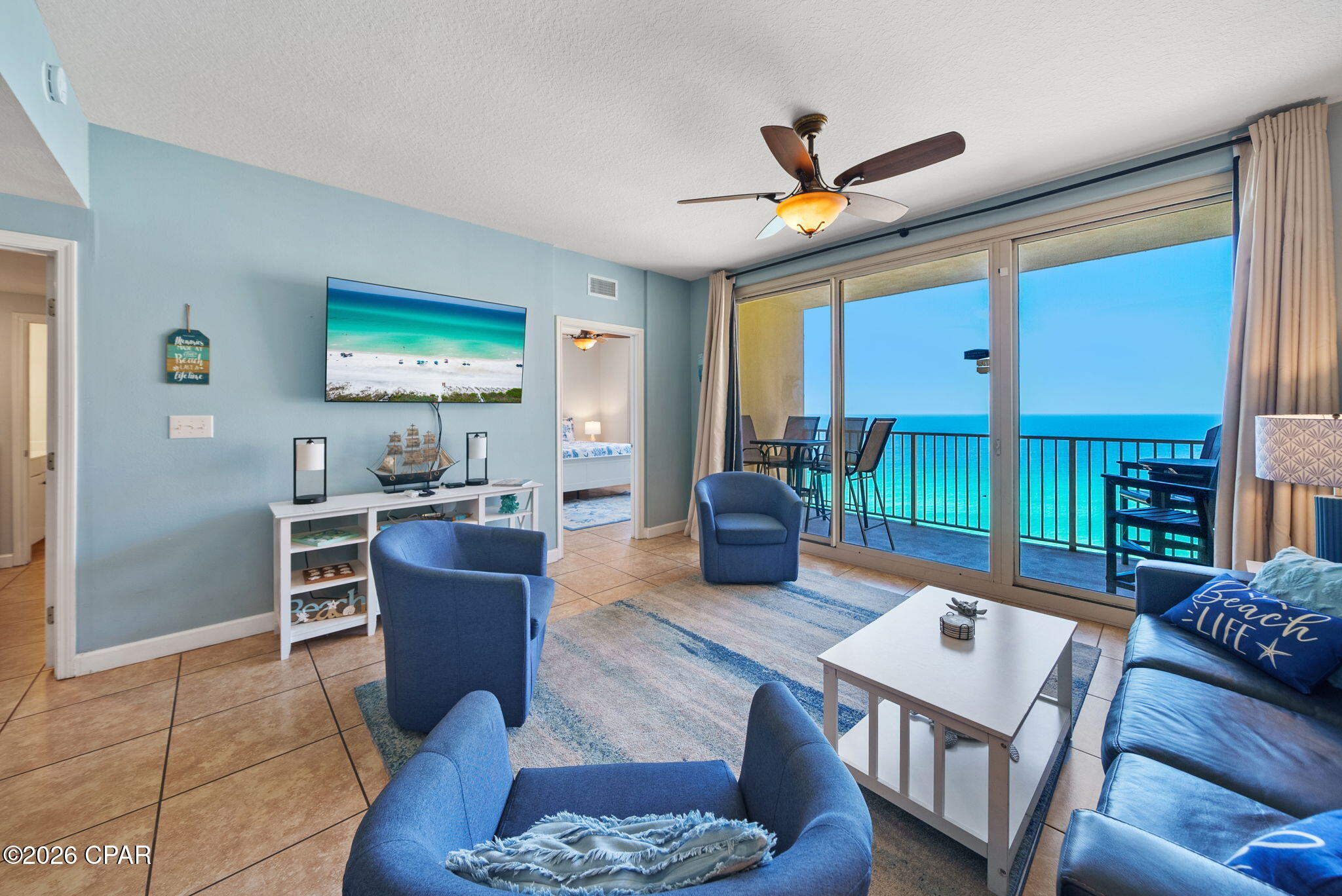 Beachfront condo living room with blue seating and sliding doors overlooking the ocean.