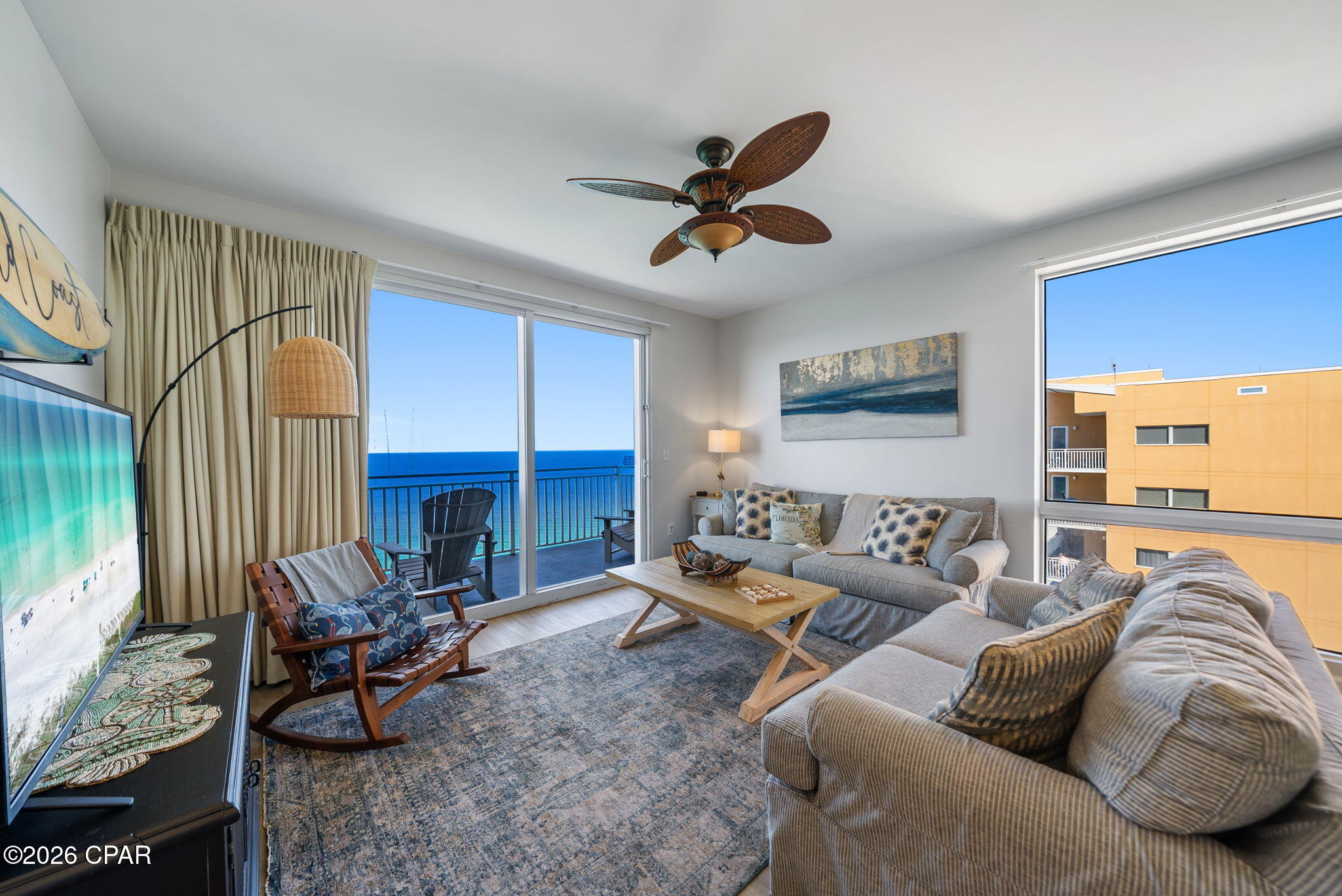 Condo living room with gray sofas and a balcony overlooking the ocean.