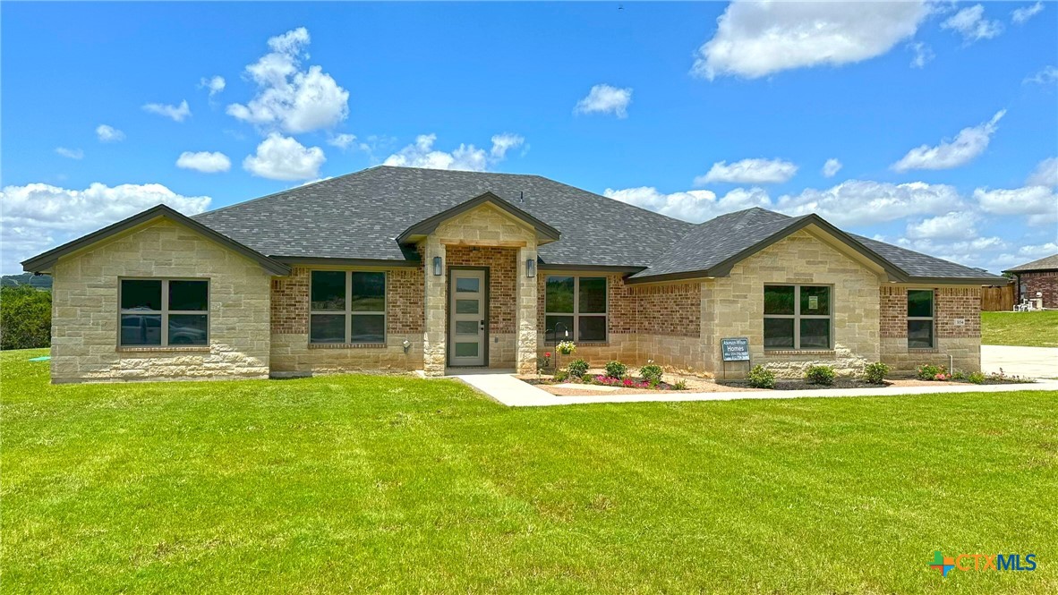 Single-story stone and brick home with a broad gray roof and landscaped front lawn.