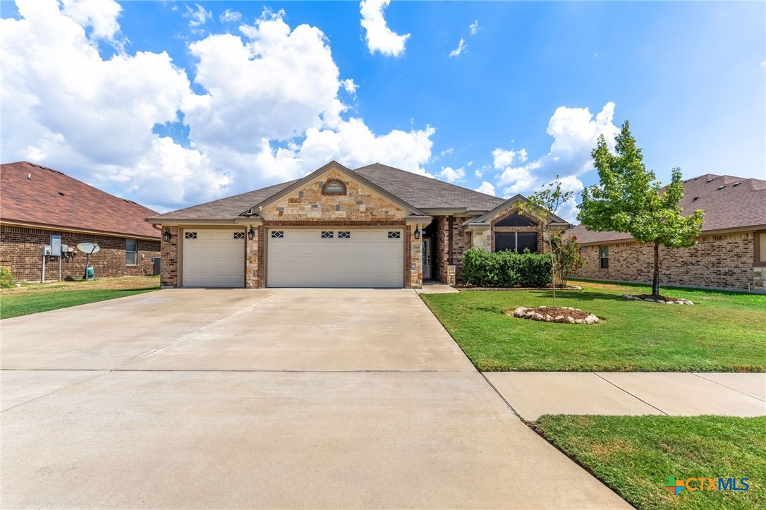 Single-story brick and stone home with a two-car garage, broad driveway, and landscaped front lawn.