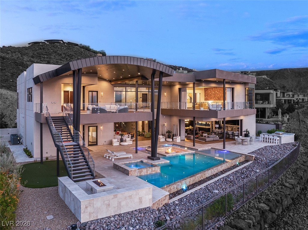 Modern hillside home with curved roofline, glass walls, and a multi-level pool.