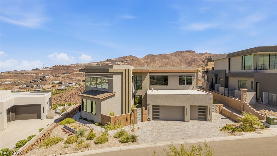 Modern two-story home with a broad driveway and desert hills behind it.