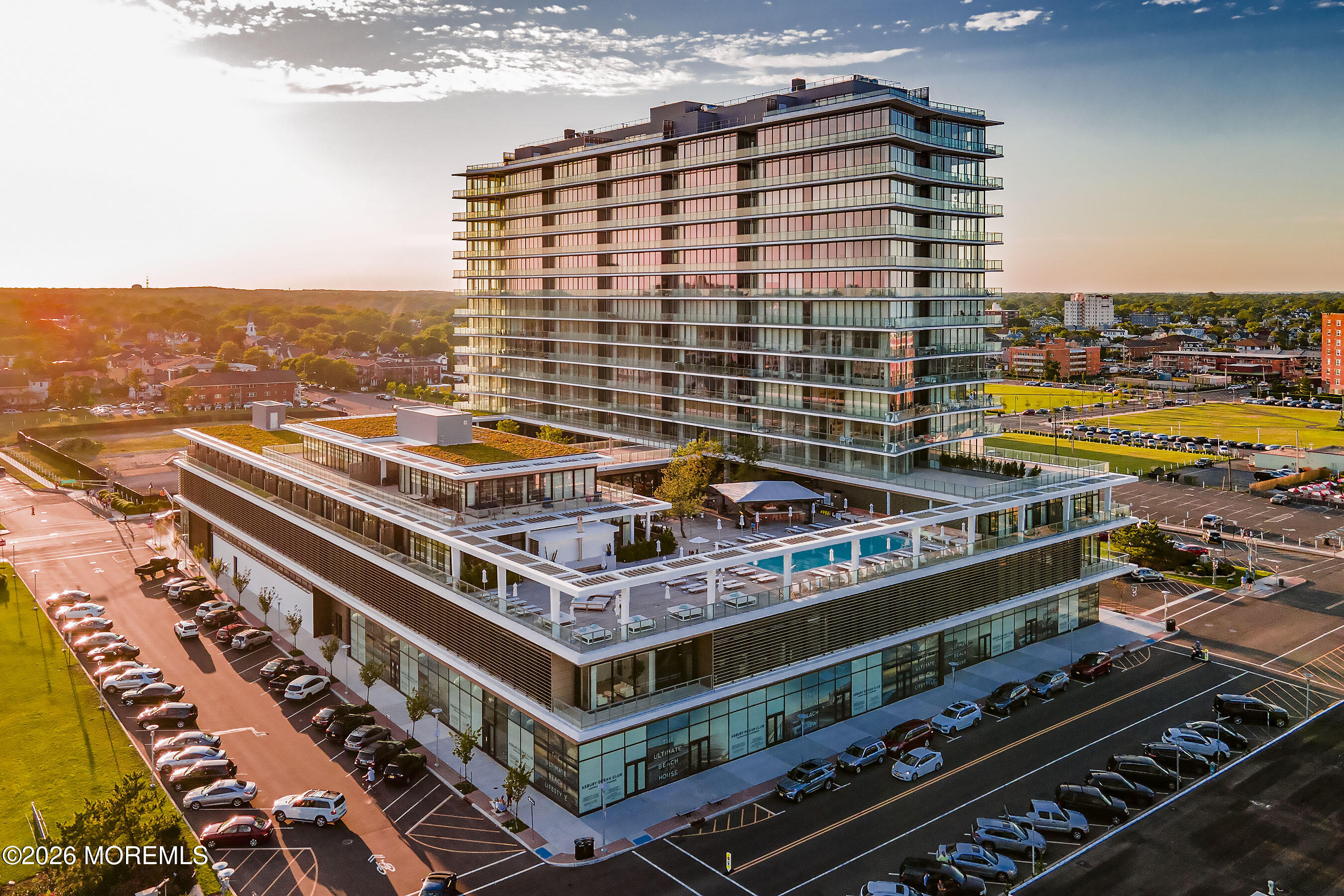 Modern glass condominium tower above a podium with an outdoor pool and terraces.