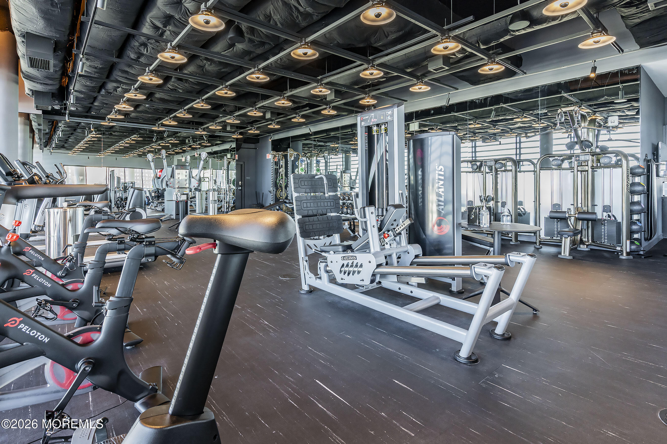 Gym with Peloton bikes in front and Atlantis strength-training equipment throughout.