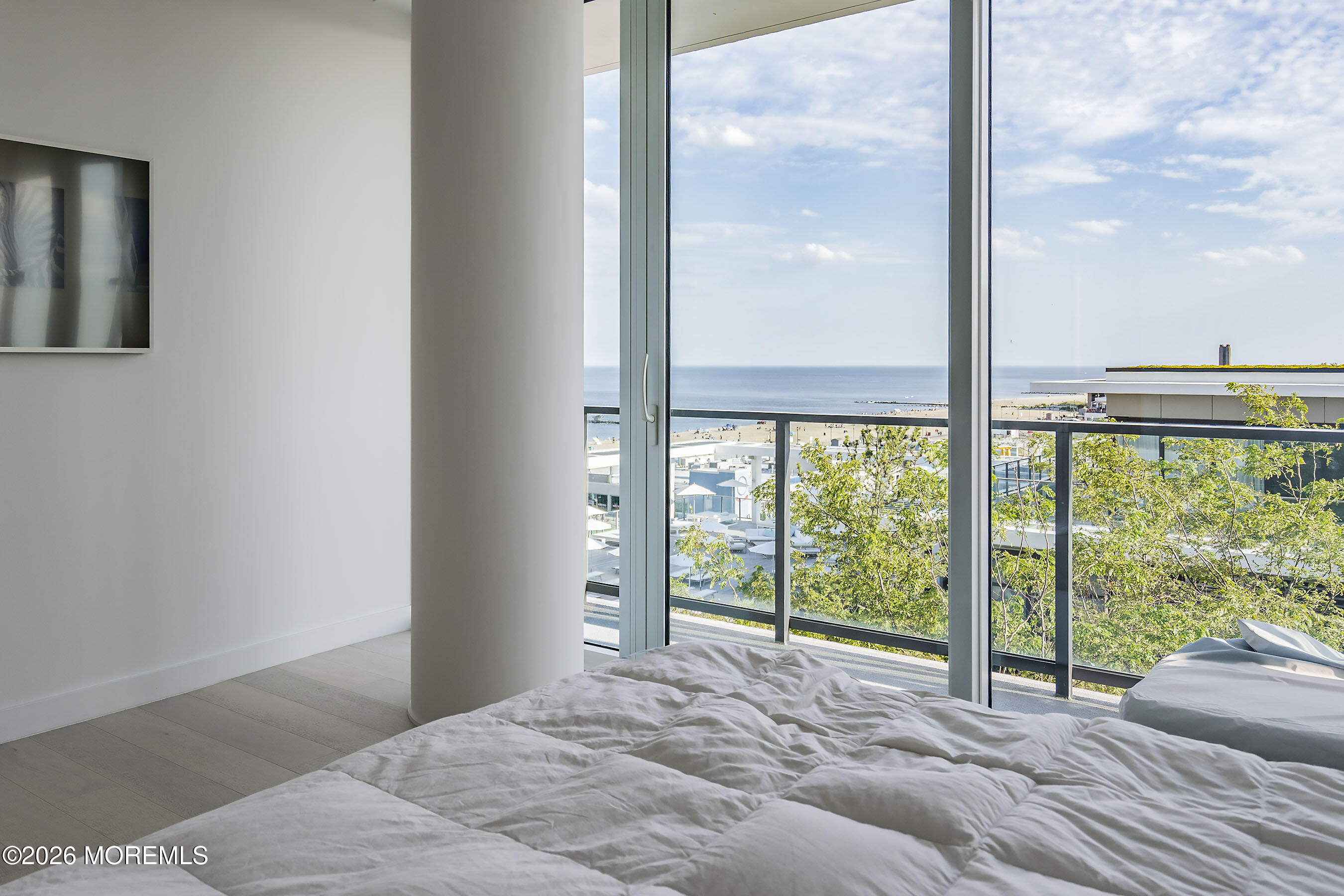 Bedroom with floor-to-ceiling windows overlooking the ocean and beach.