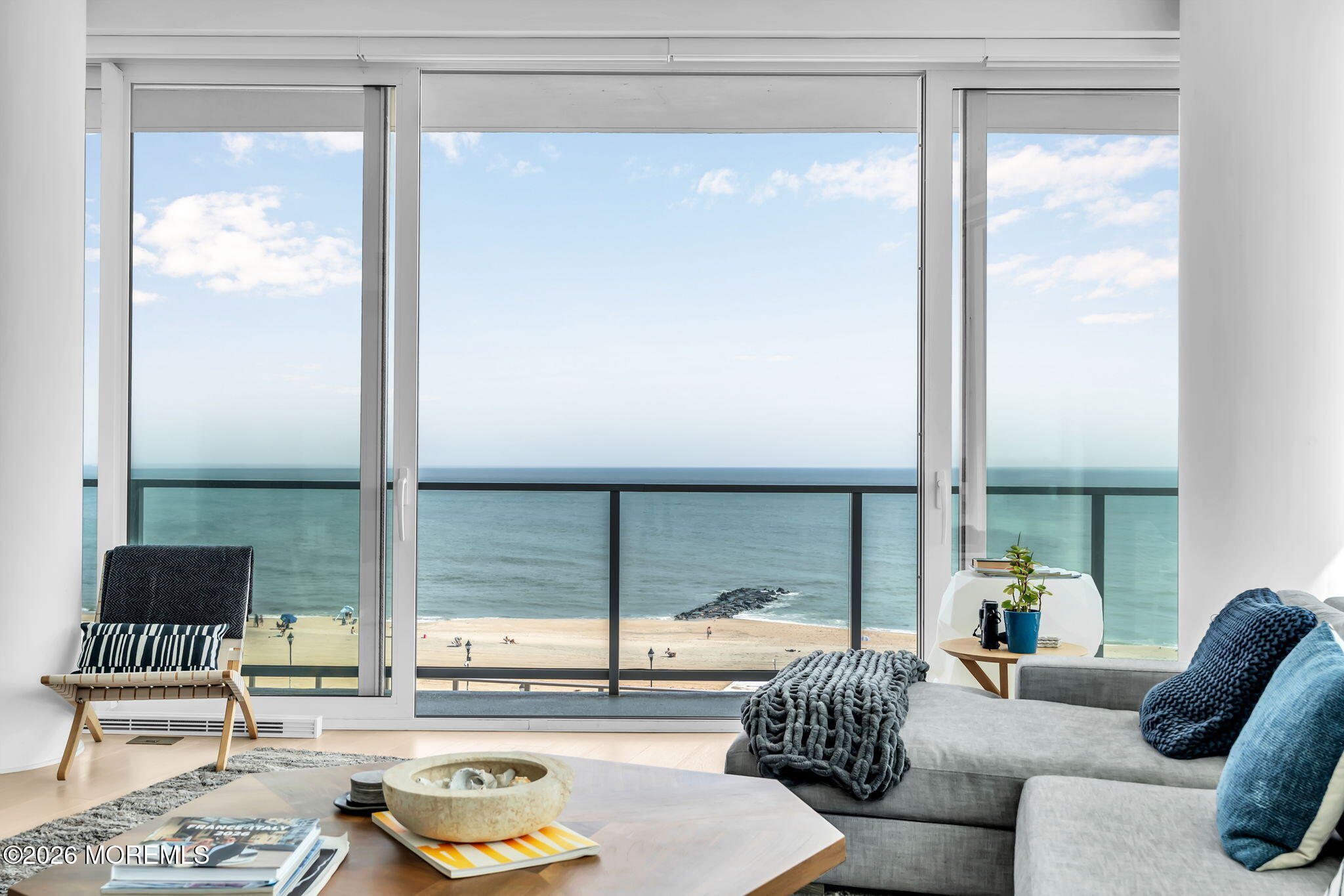 Living room with floor-to-ceiling windows overlooking the ocean and beach.