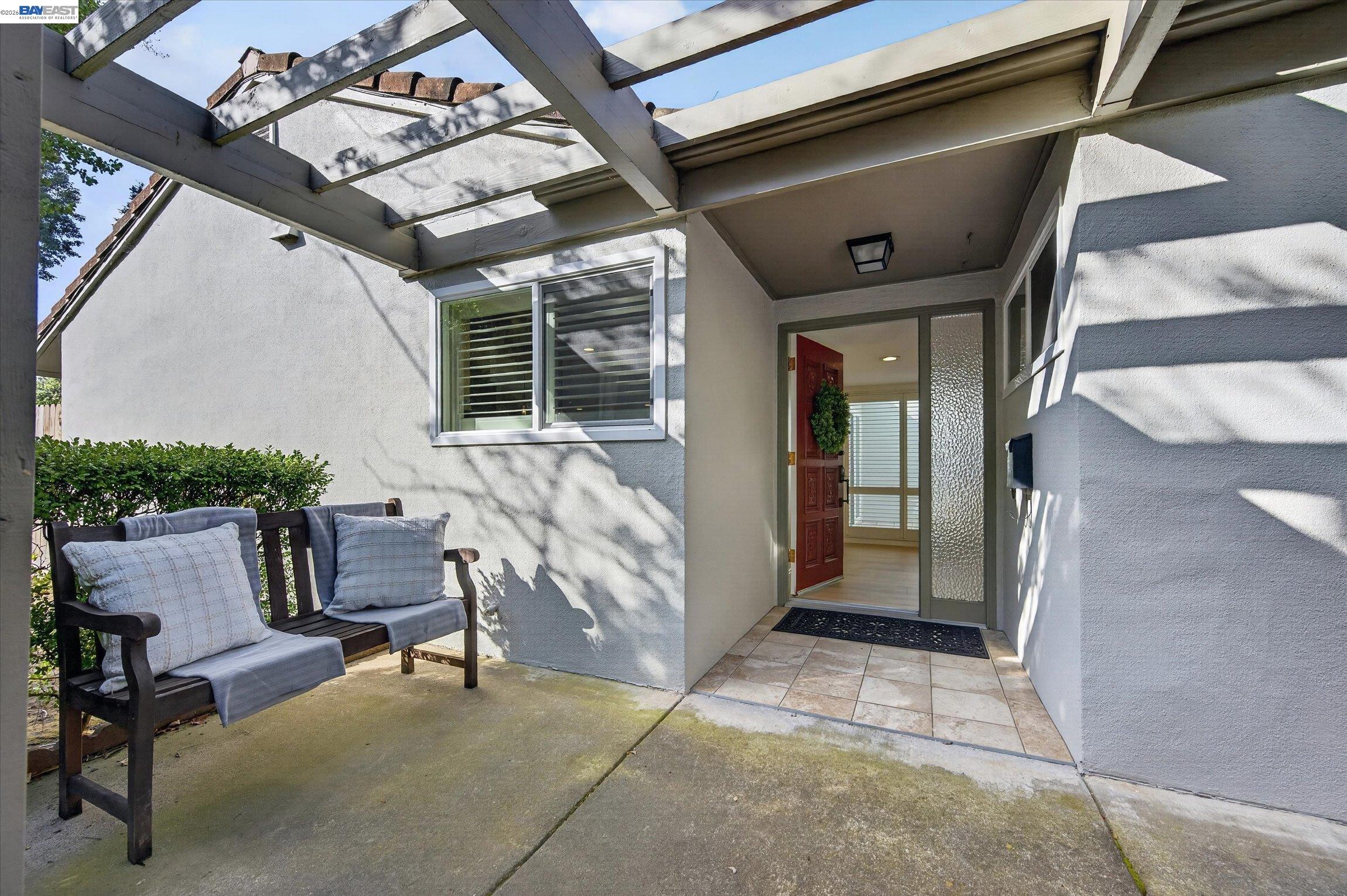 Covered front entry with a cushioned bench beside the open front door.