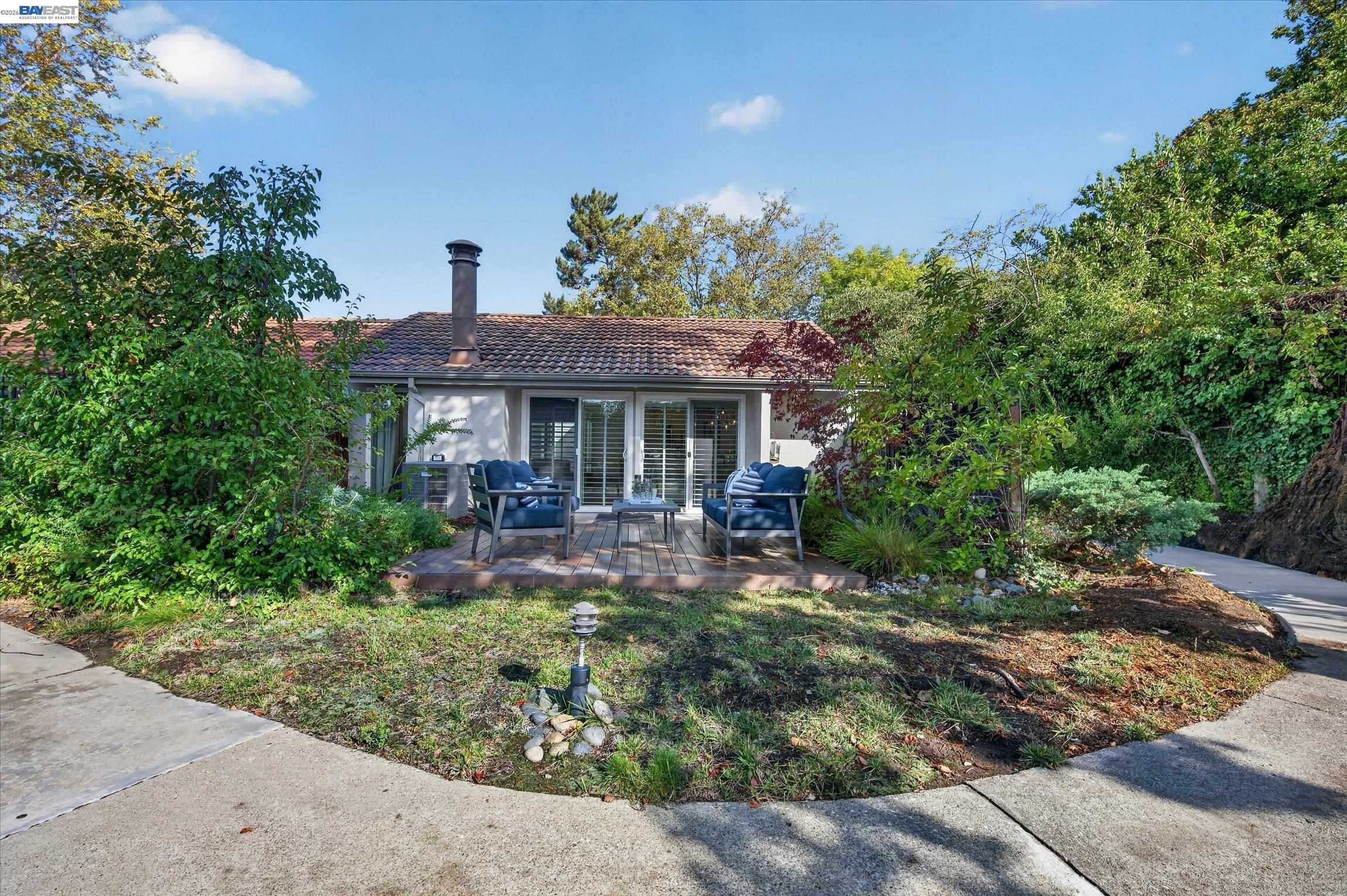 Single-story home with a tiled roof and a wood deck furnished with blue outdoor seating.