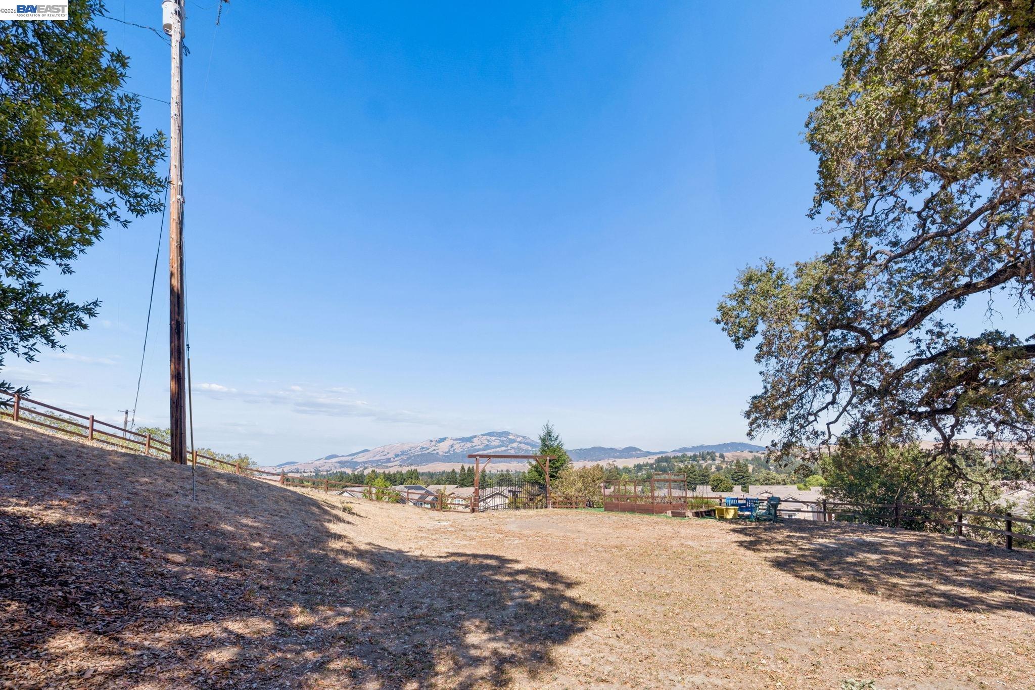 Open sloping lot with a wooden fence, timber entrance structure, and distant mountain views.