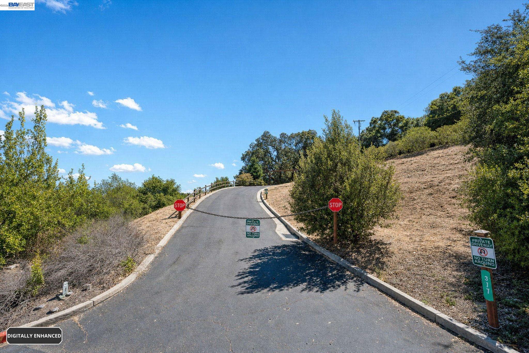 Private driveway winding uphill to a chain gate, with stop signs and a no-turnaround sign.
