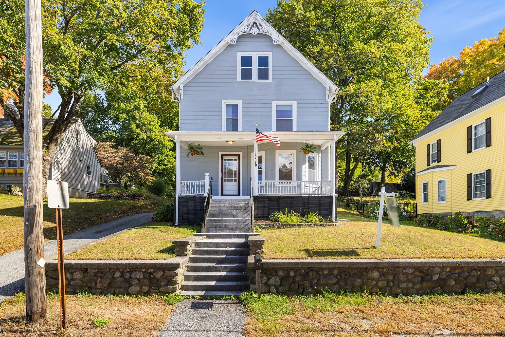 Gray two-story house with ornate gable trim, a covered porch, and stone steps.