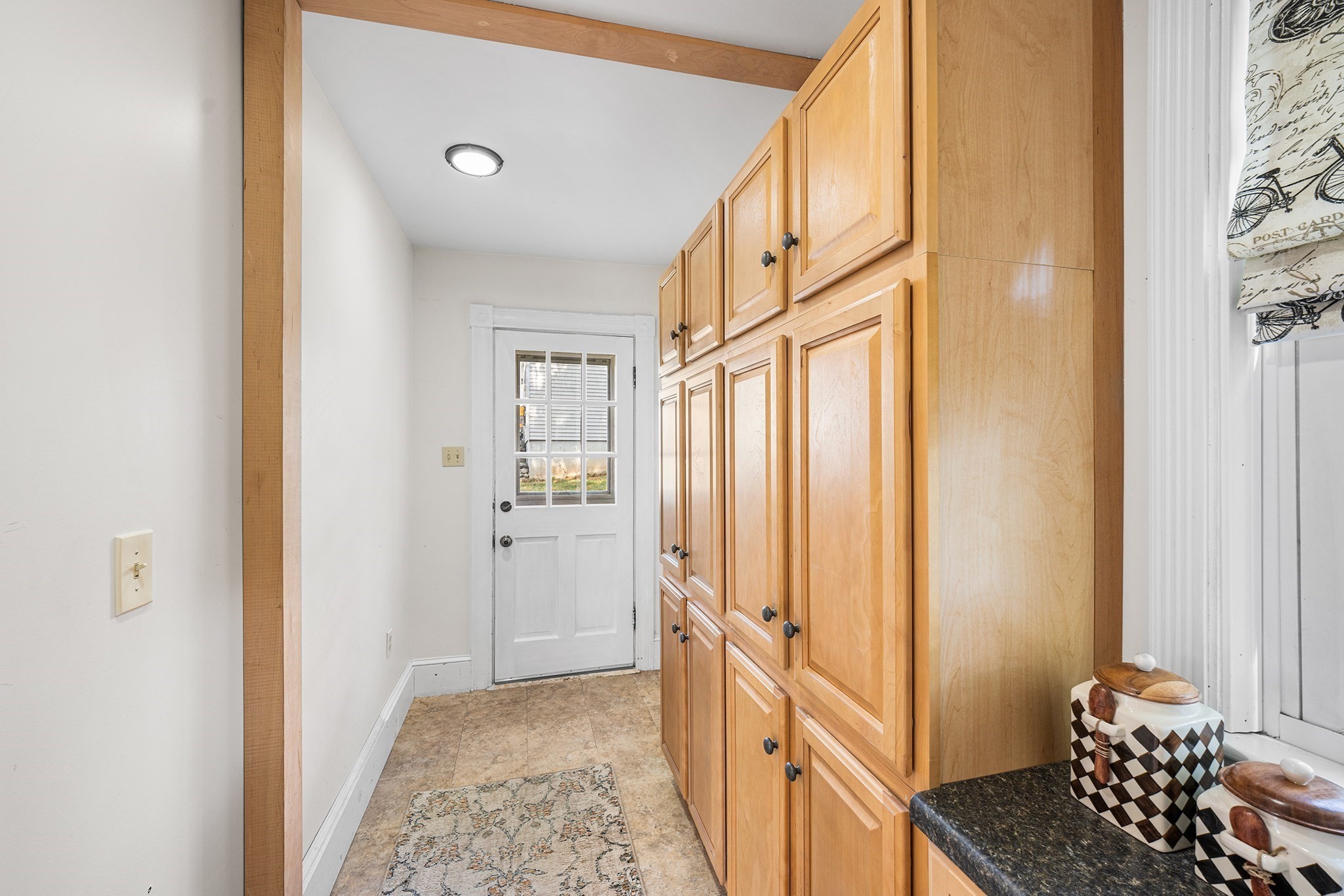 Kitchen with honey-colored cabinets, dark countertop, and a windowed exterior door.