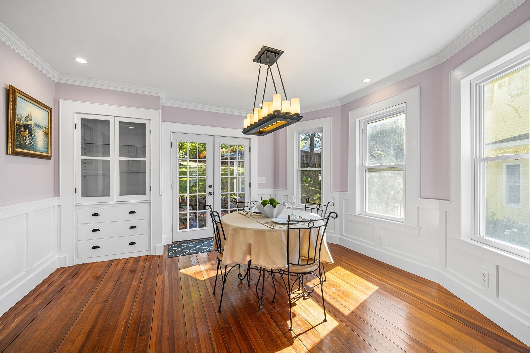 Dining room with a round table, built-in cabinetry, French doors, and sunlit hardwood floors.