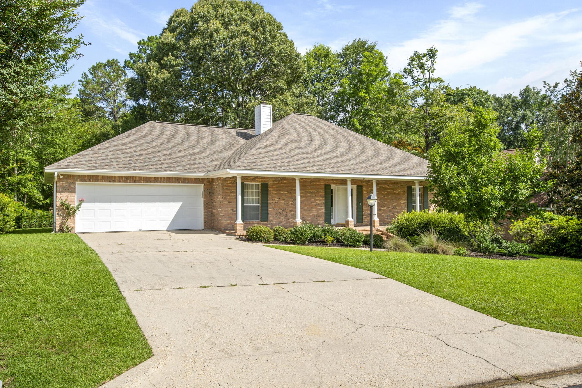 Brick ranch home with a two-car garage, covered porch, and wide concrete driveway.