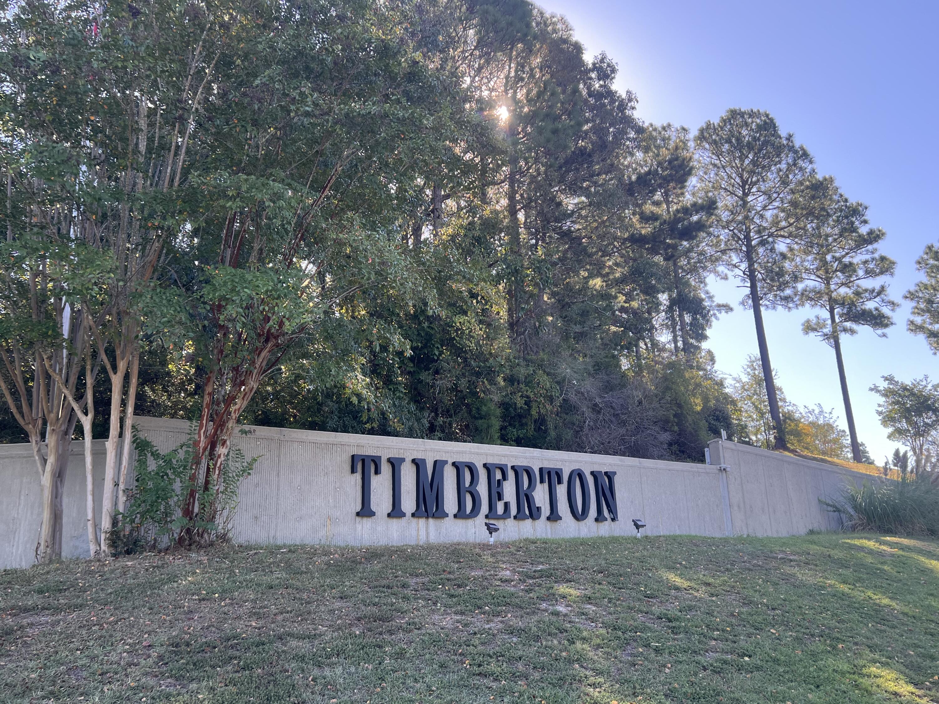 Timberton neighborhood sign on a landscaped wall beneath tall trees.