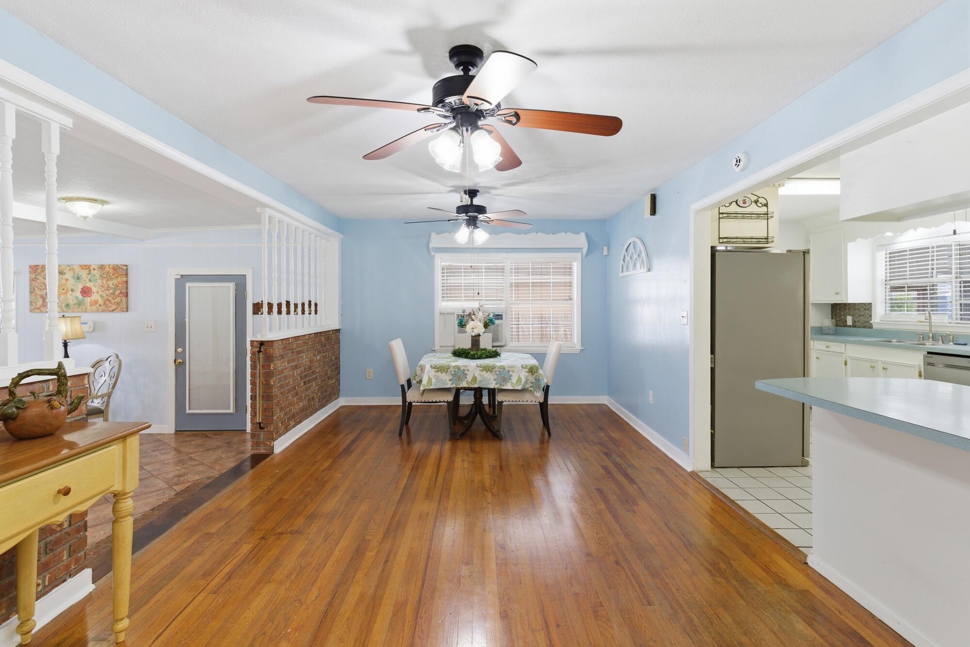 Dining area with blue walls, hardwood floors, a round table, and an open kitchen.