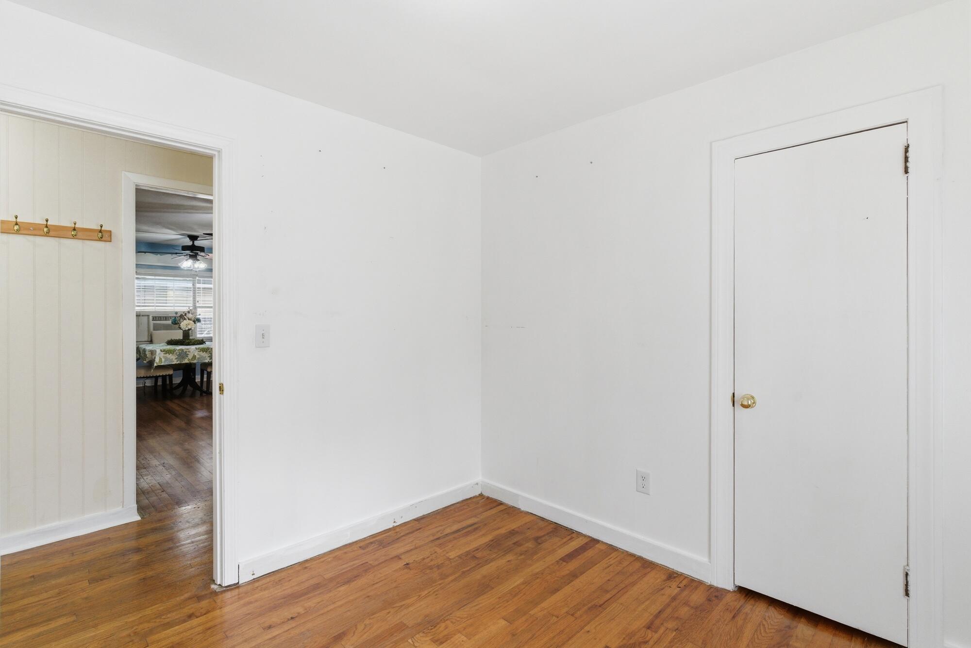 Empty room with hardwood floors and a doorway to an adjoining dining area.