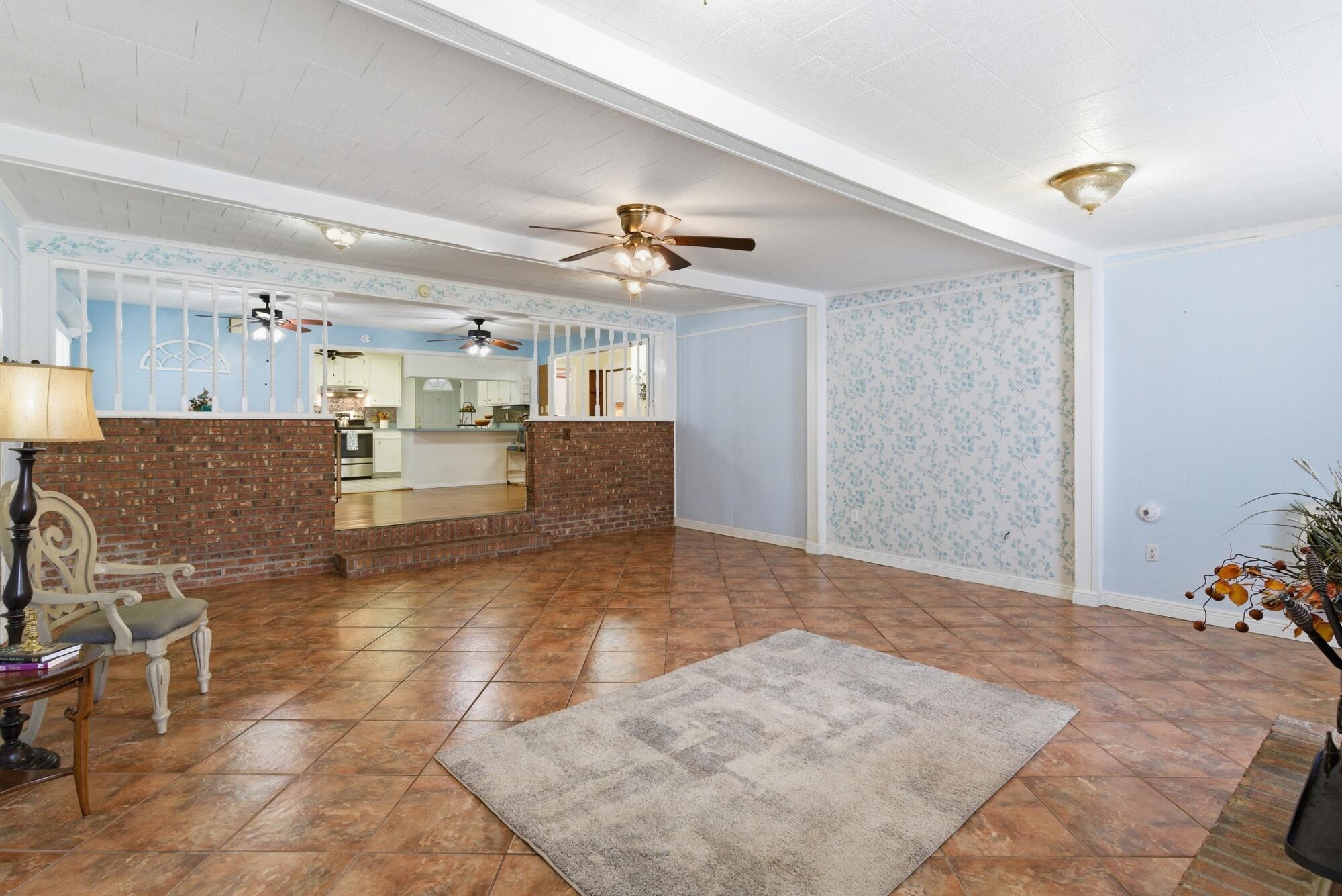 Living area with terracotta tile floors and brick half-walls opening to the kitchen.