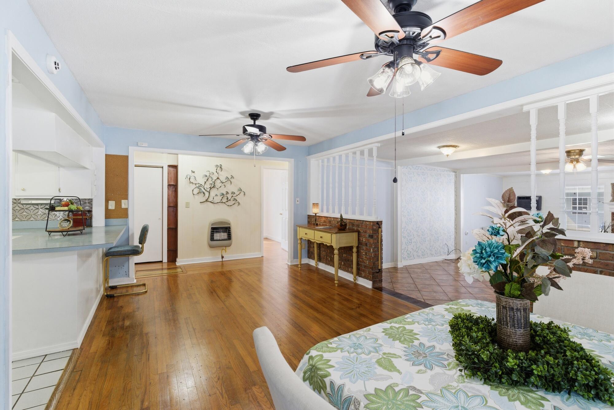 Open dining area with a floral table setting, hardwood floors, and a kitchen breakfast bar.