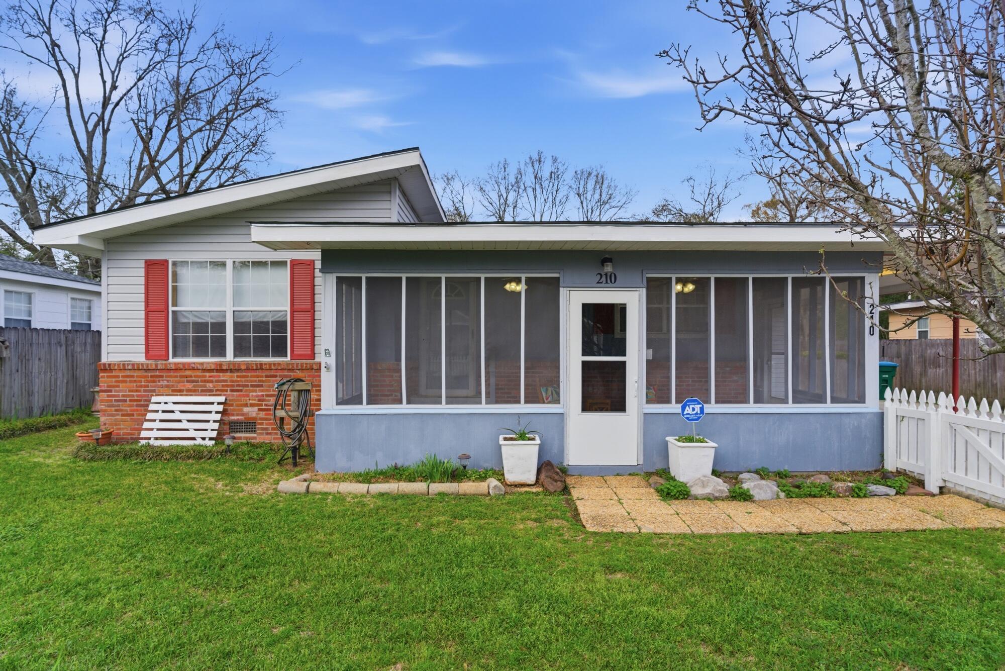 Single-story home with a wide screened porch, red shutters, and brick façade.