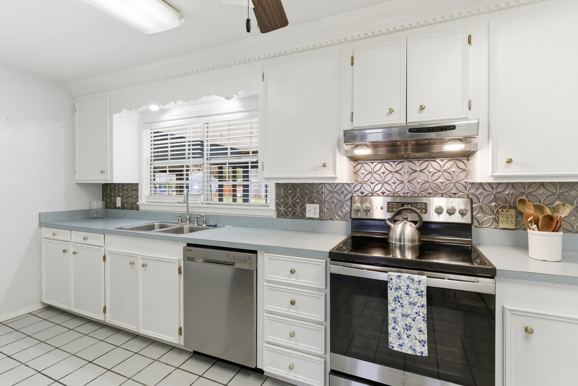 Kitchen with white cabinets, a patterned metallic backsplash, and stainless steel appliances.