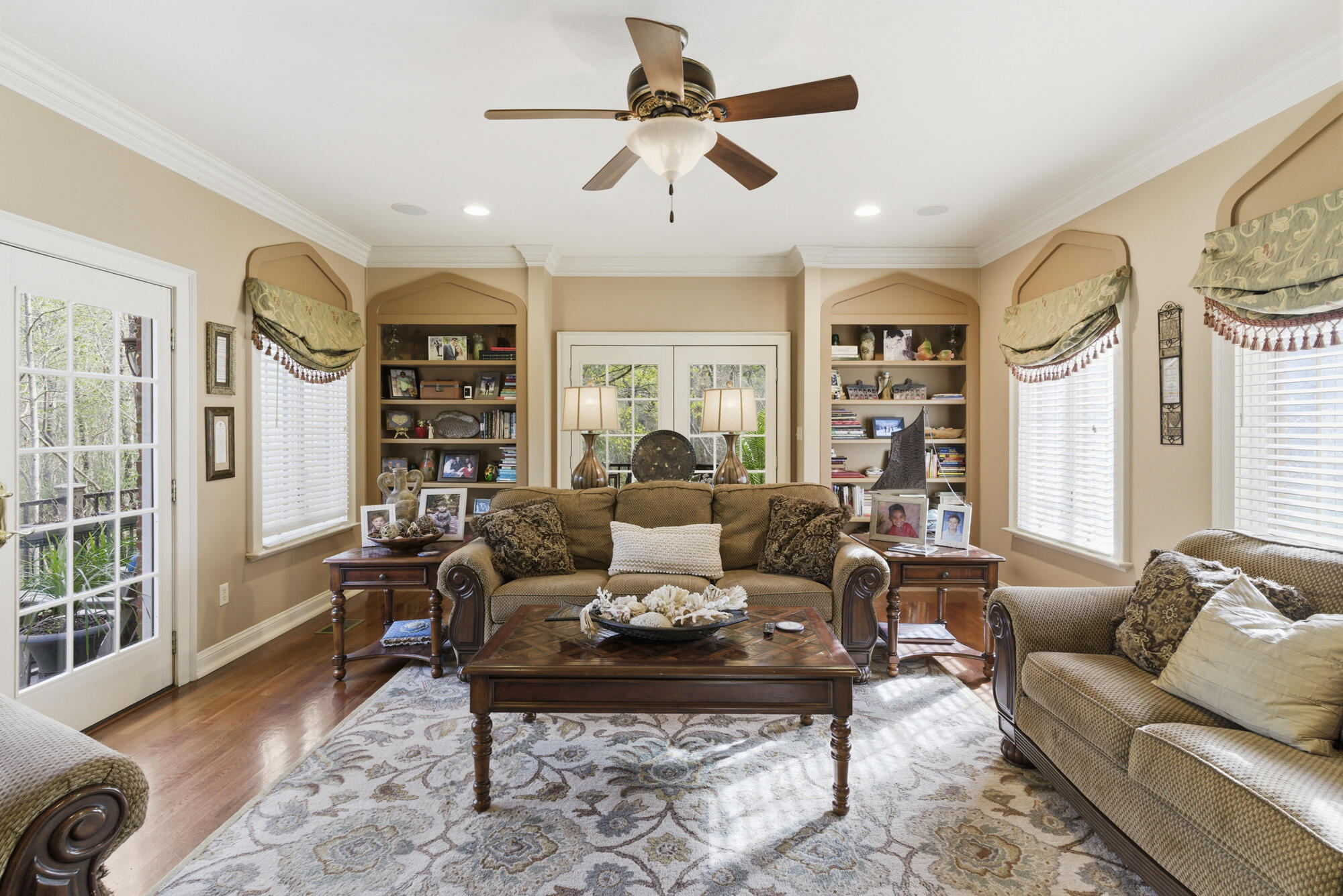 Furnished living room with built-in bookshelves, a patterned rug, and a ceiling fan.