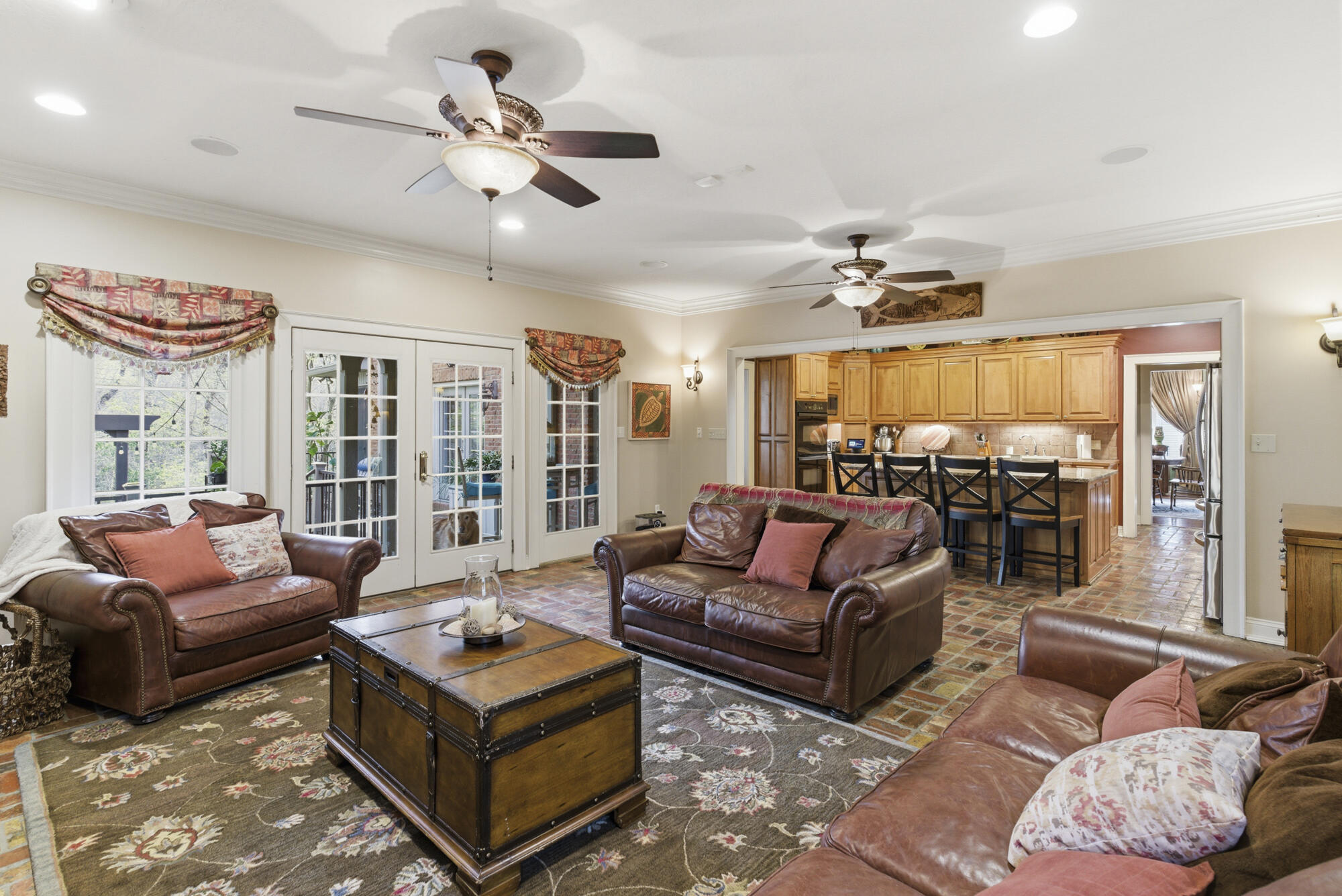 Living room with leather sofas and trunk coffee table opens to a kitchen with a bar island.