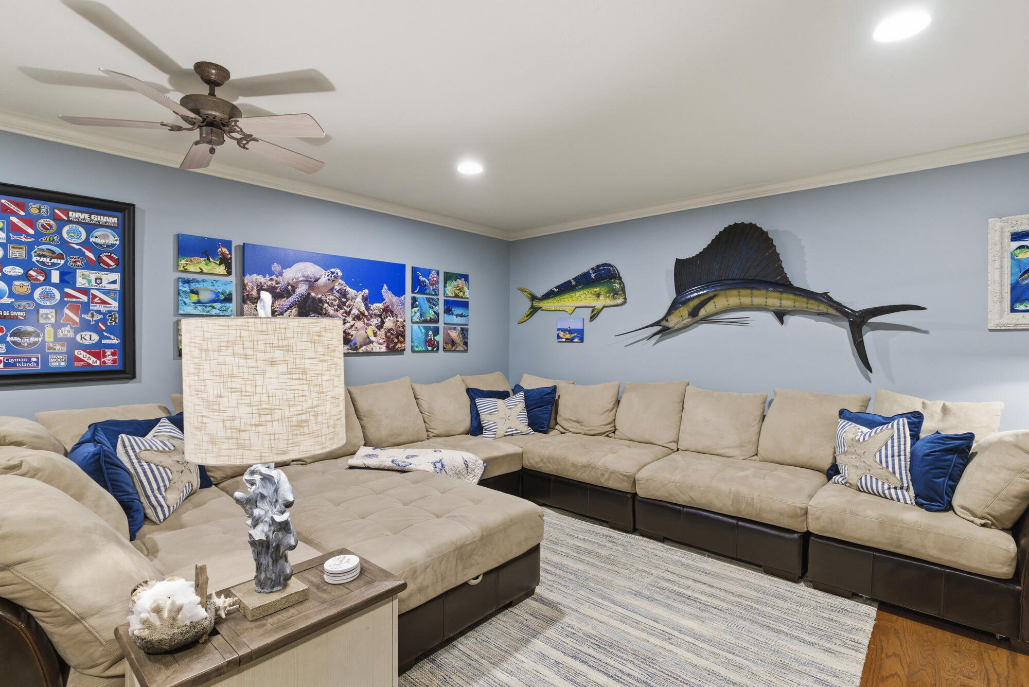 Living room with a beige sectional sofa and prominent fish sculptures on blue-gray walls.