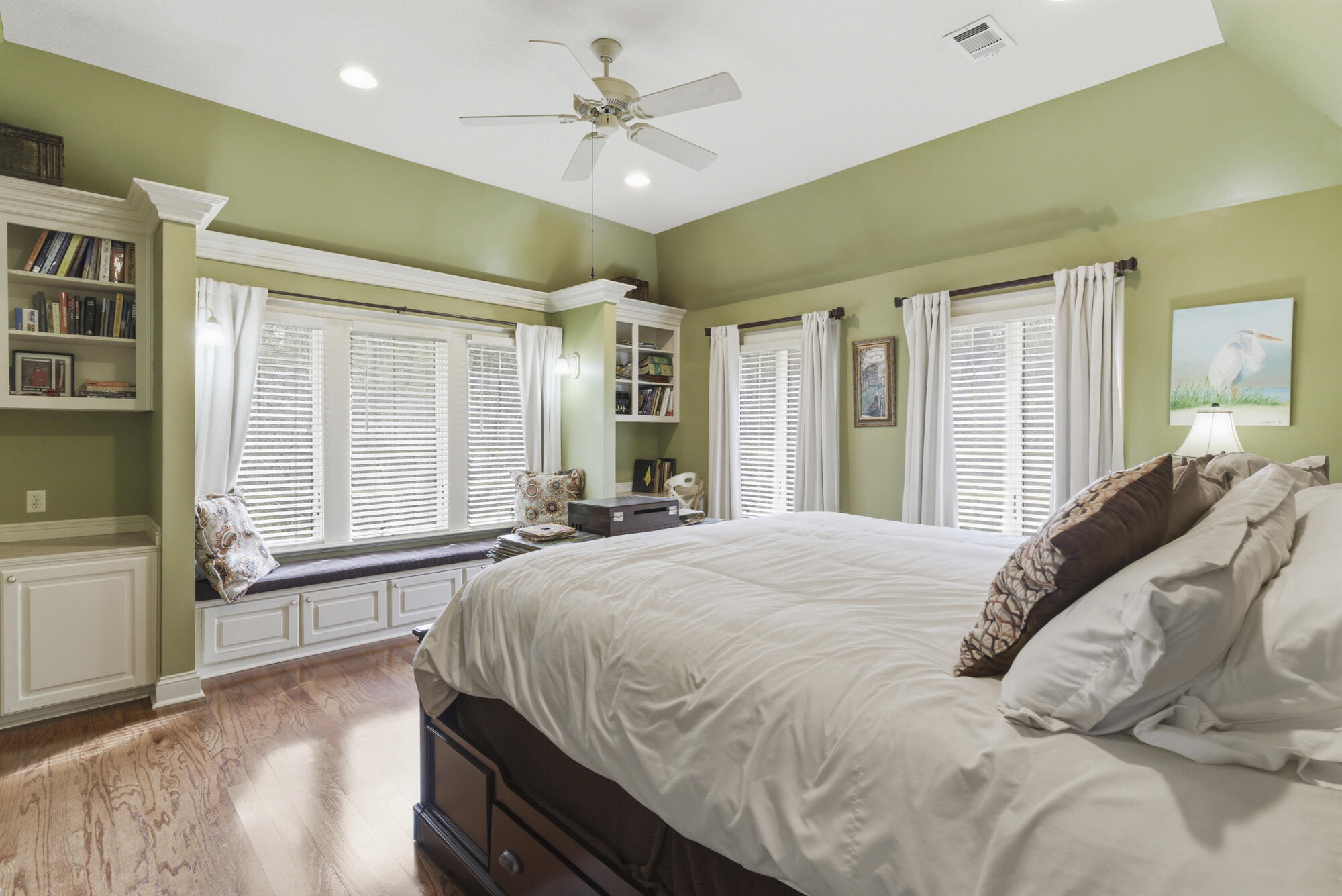 Bedroom with a large bed, built-in window seat, and sage-green walls.
