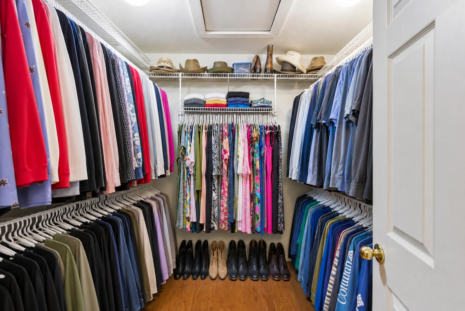 Walk-in closet with extensive clothing storage, folded clothes, hats, and shoes.