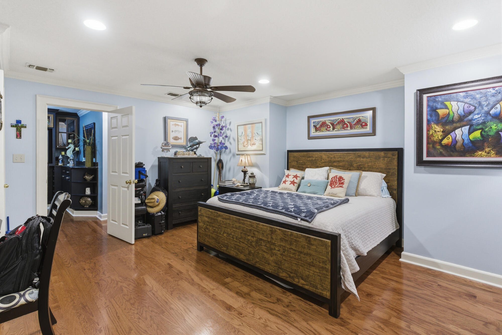 Bedroom with a dark wood bed, hardwood floors, and framed fish artwork on pale blue walls.