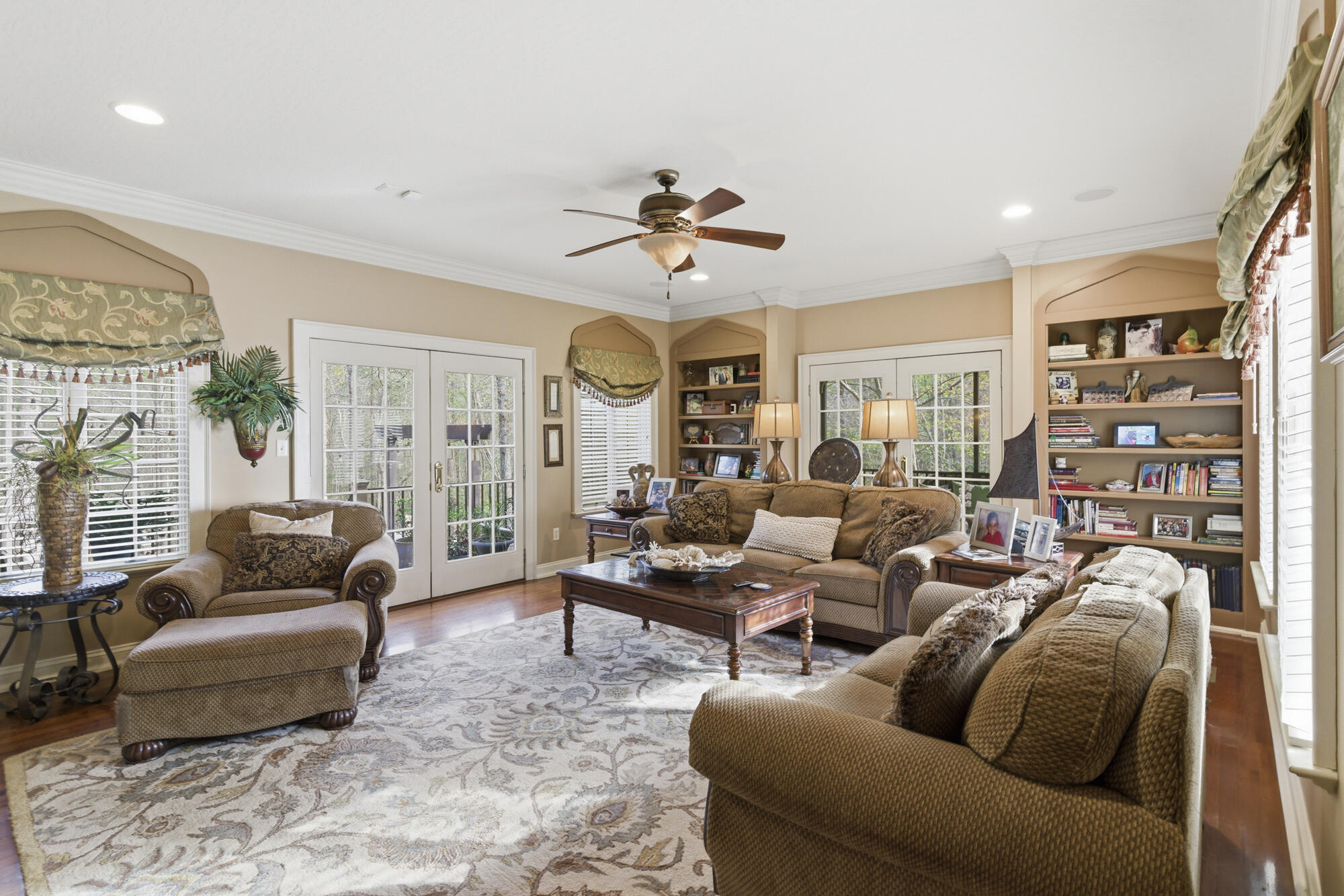 Furnished living room with brown seating, built-in bookshelves, and French doors.