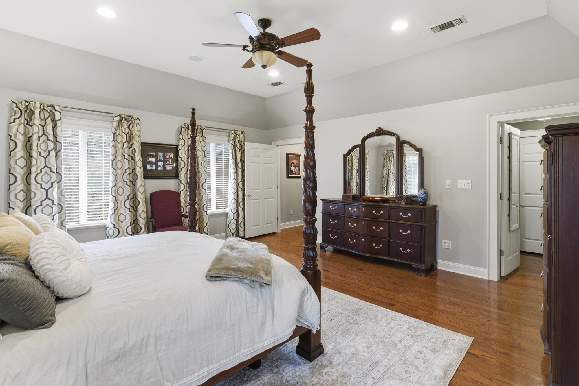 Bedroom with a dark wood four-poster bed, matching dresser and mirror, and hardwood floors.