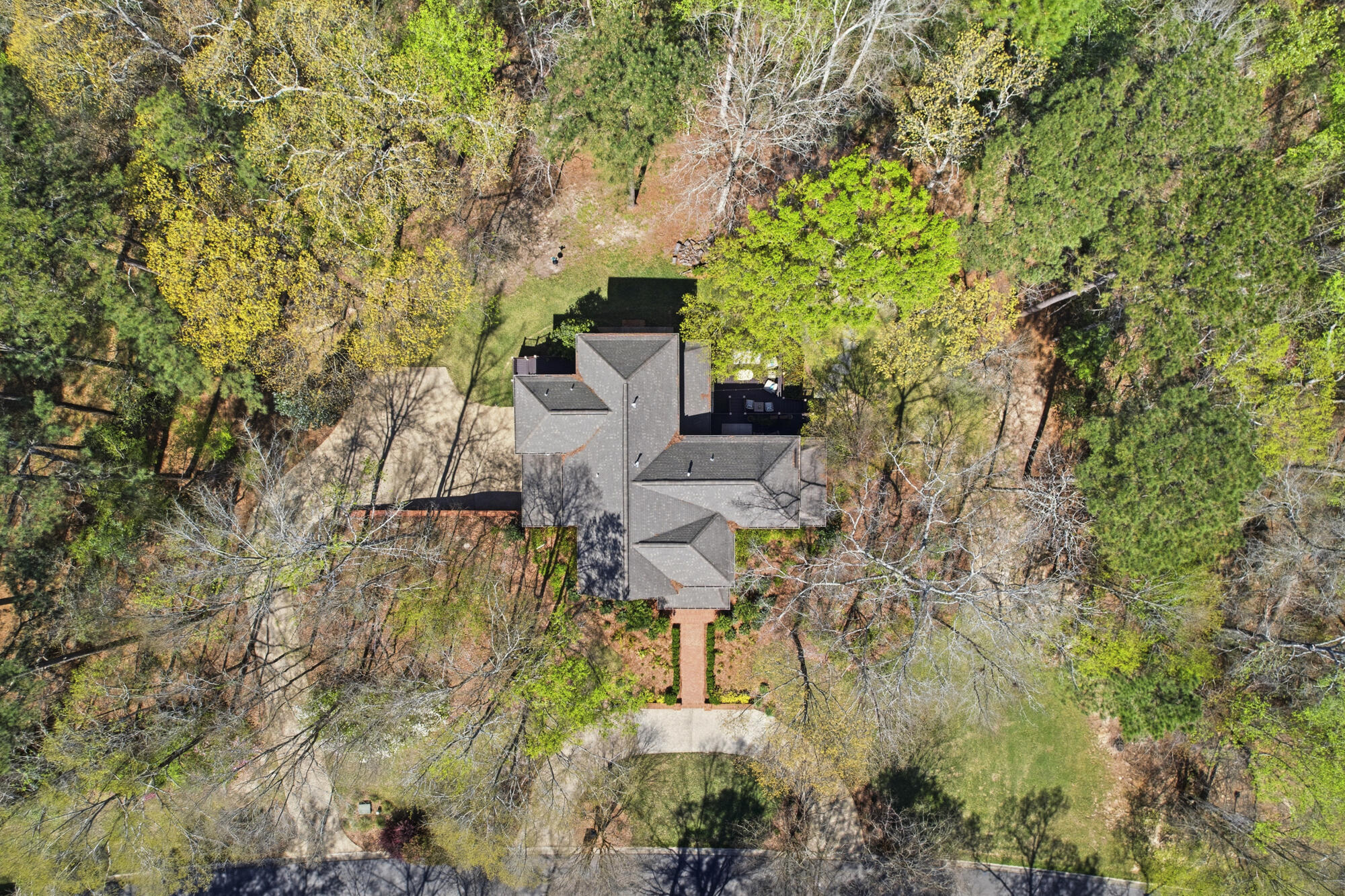 Aerial view of a large gray-roofed house surrounded by mature trees and lawn.