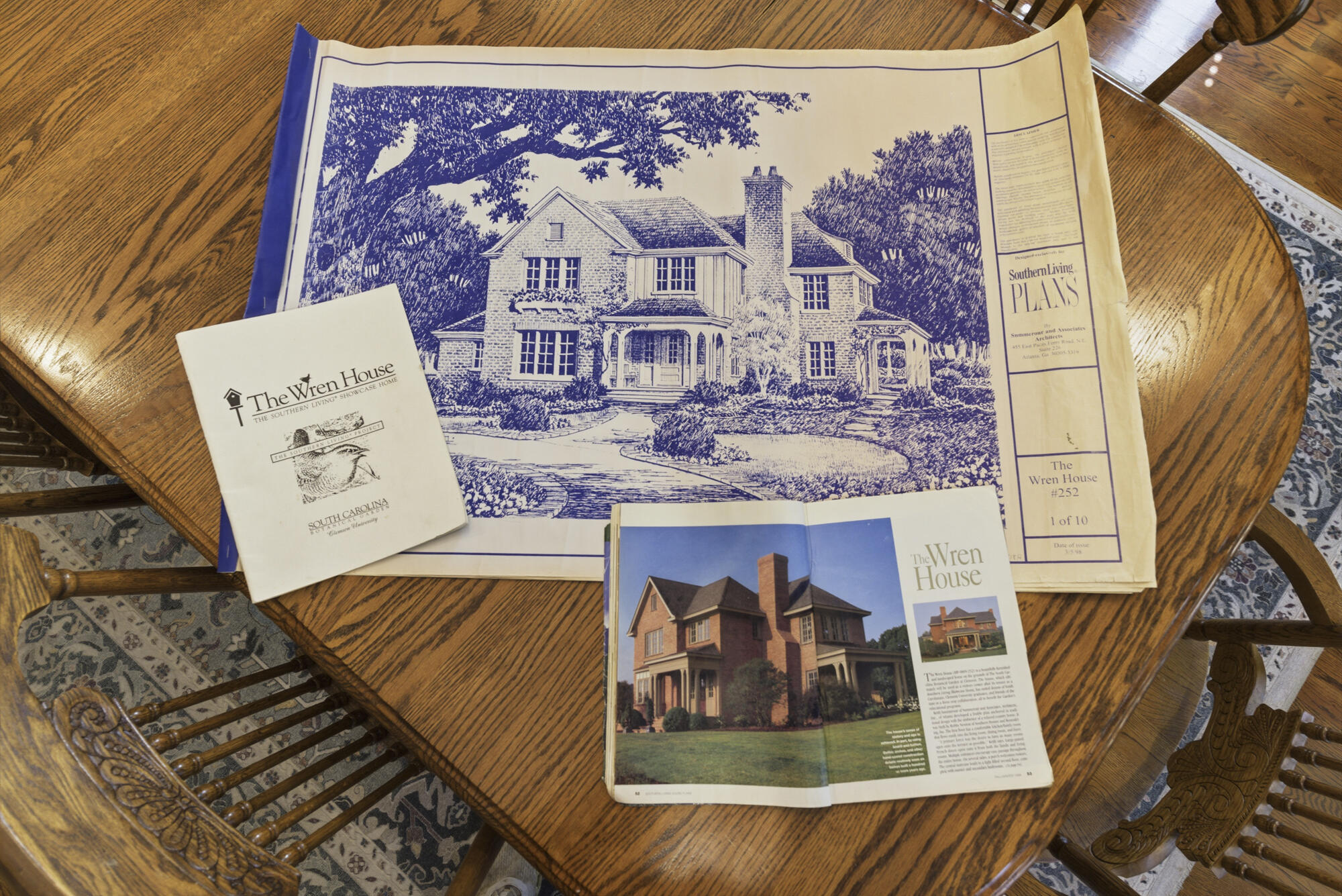 Architectural plans and publications for The Wren House spread across a wooden table.