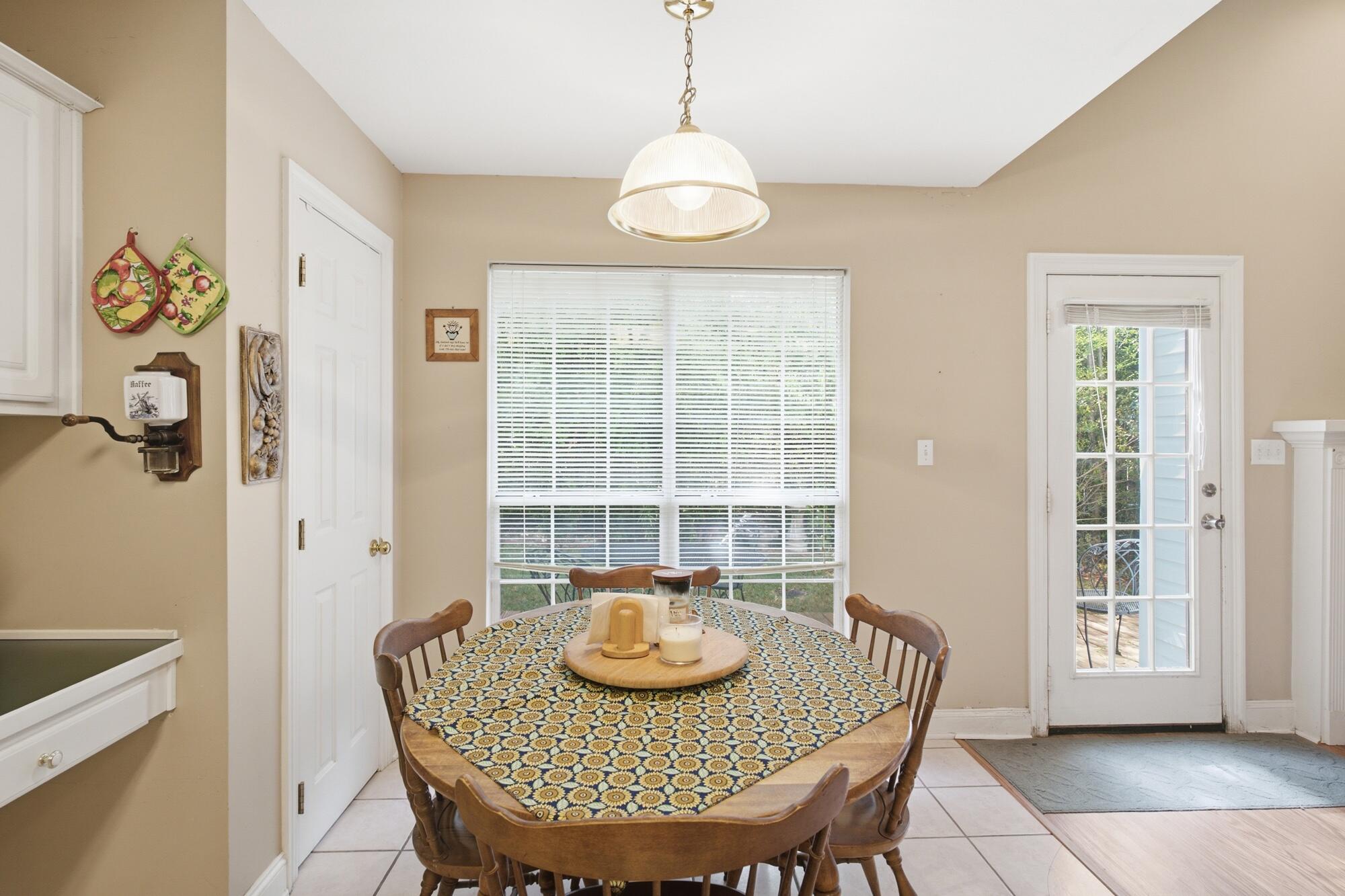 Dining area with a patterned tablecloth, large window, and glass patio door.