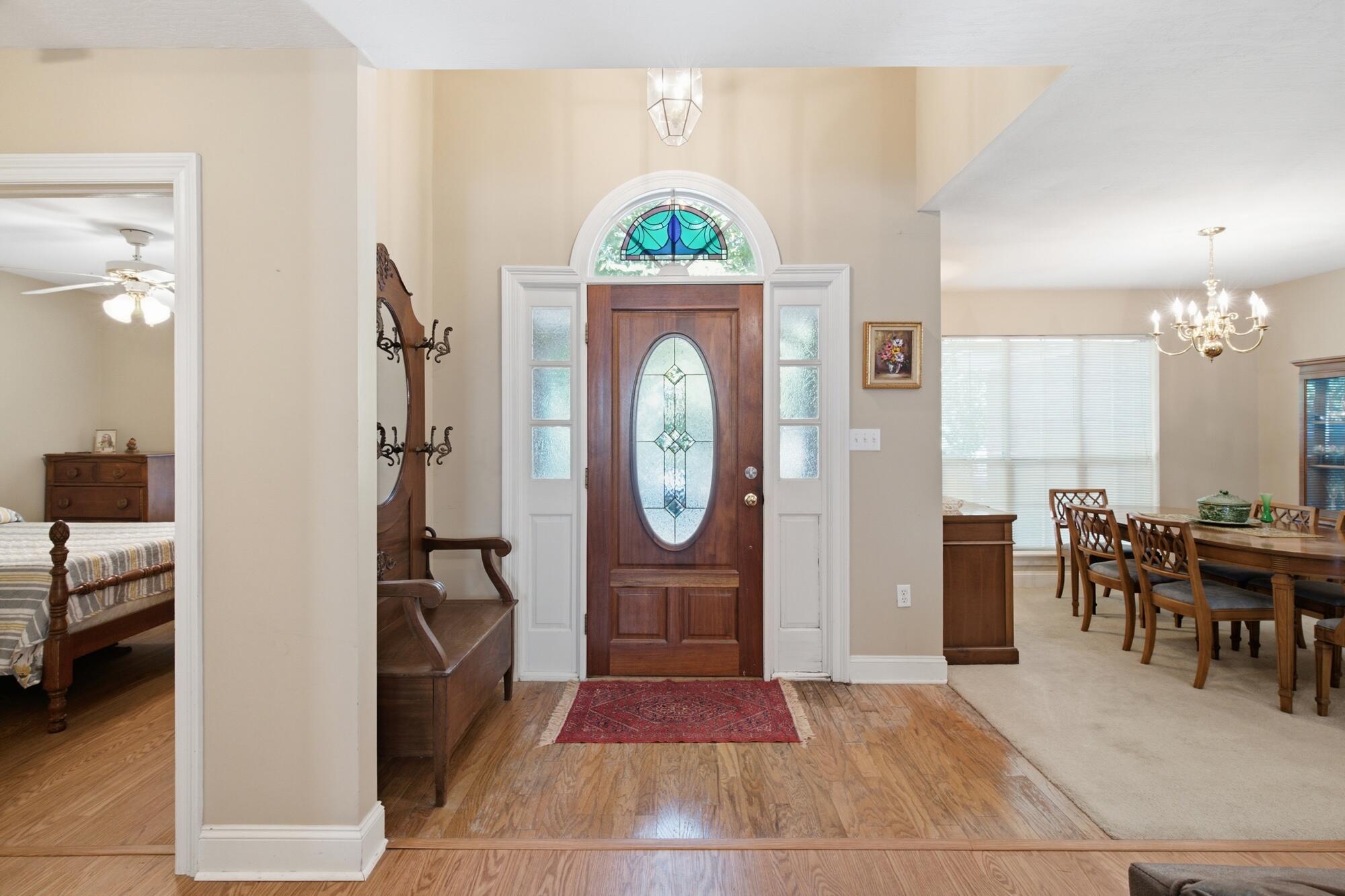 Entry foyer with a stained-glass front door, hardwood floors, and dining area.