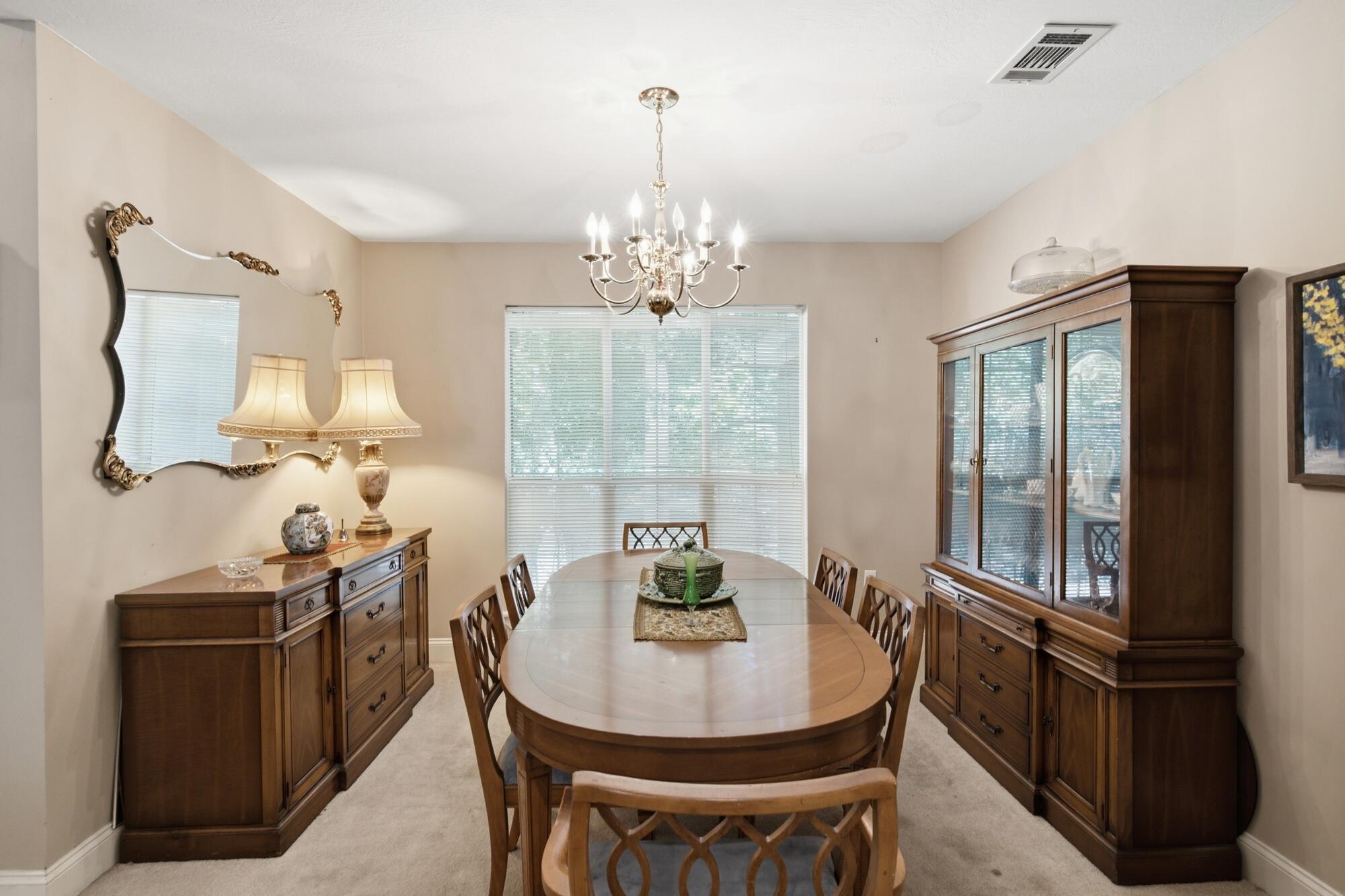 Dining room with an oval wooden table, matching china cabinets, and a chandelier.