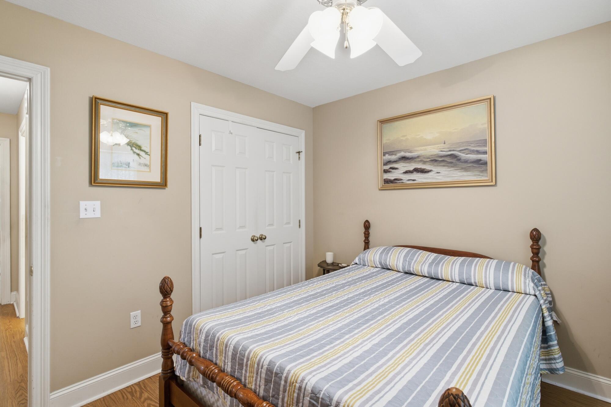 Bedroom with a wooden four-poster bed, striped bedding, and white double closet doors.