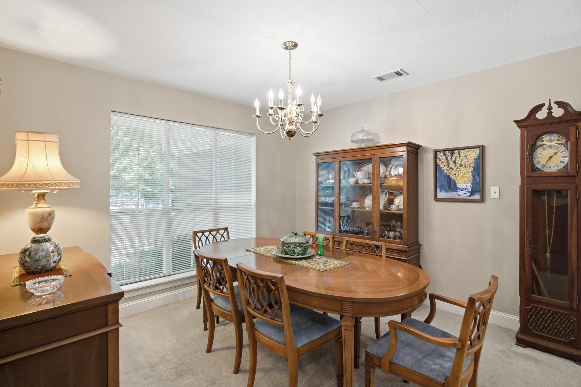 Furnished dining room with an oval wood table, chandelier, china cabinet, and grandfather clock.