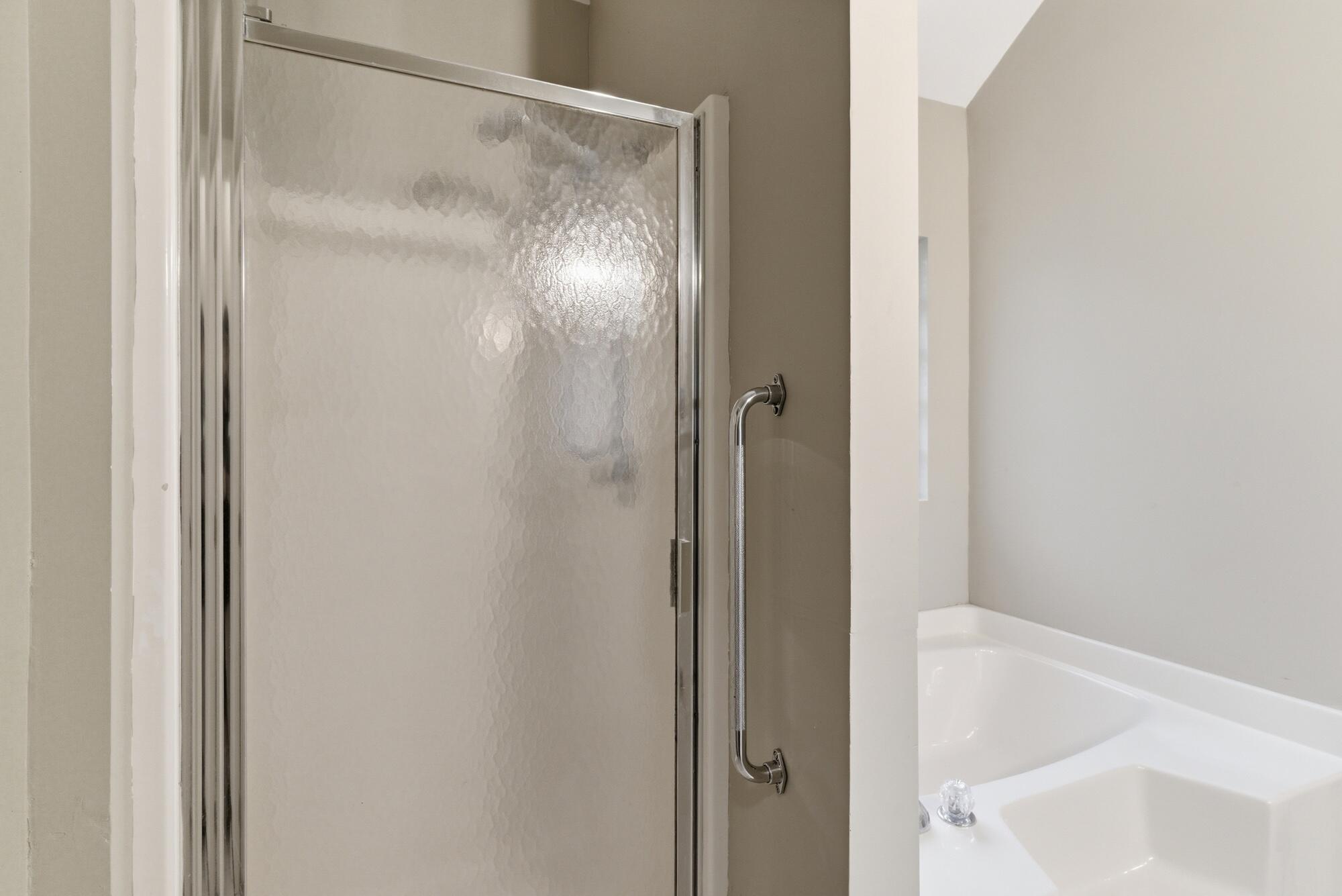 Bathroom with a frosted-glass shower enclosure beside a white soaking tub.