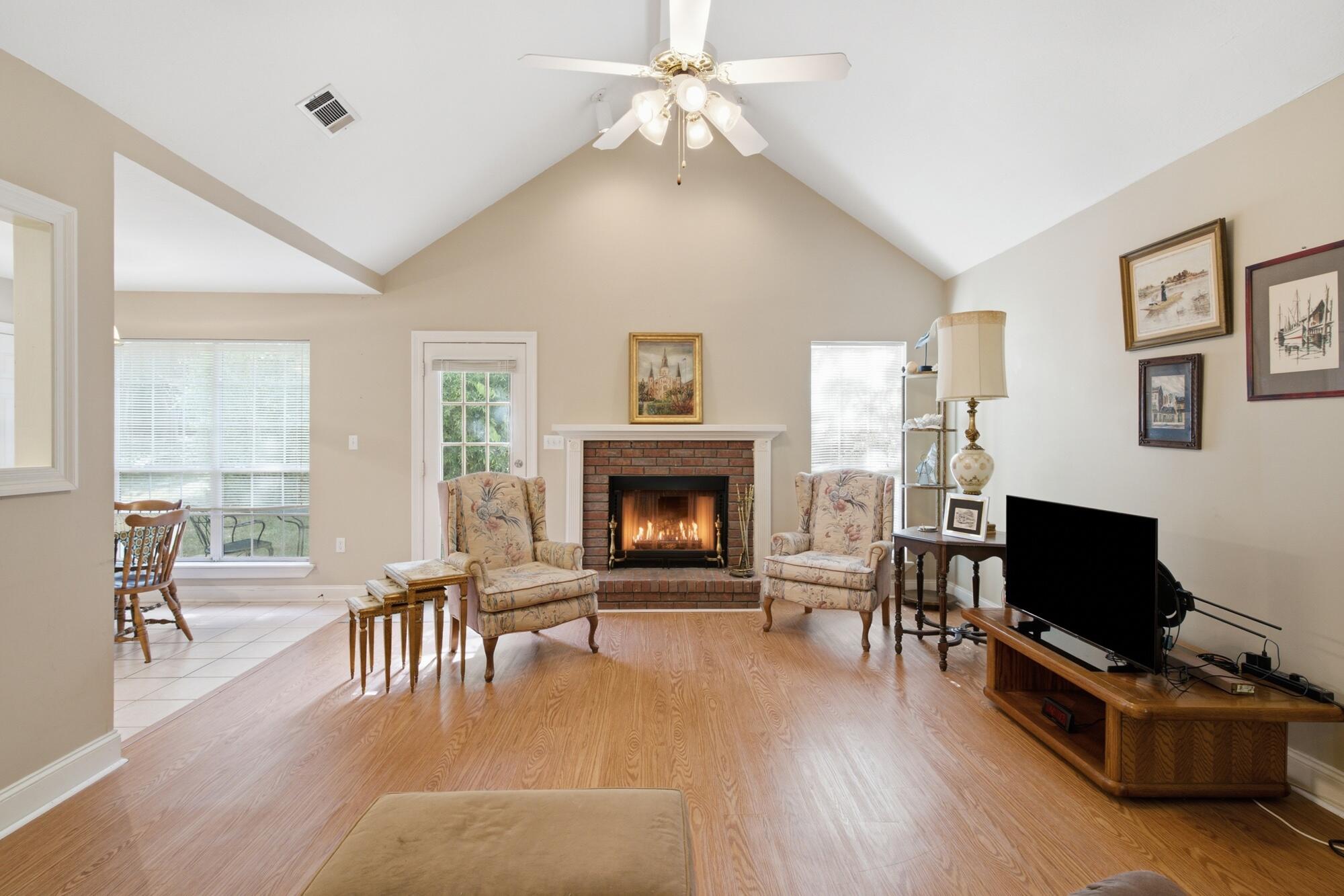 Living room with a vaulted ceiling, brick fireplace, and floral armchairs.