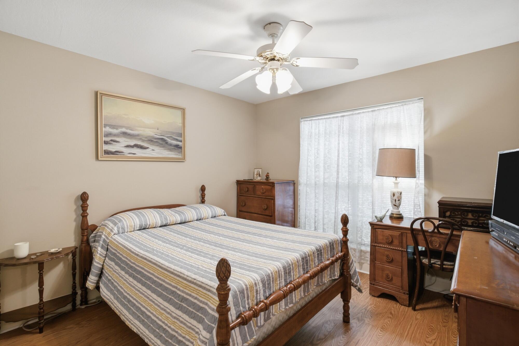 Bedroom with a wooden four-poster bed, striped bedding, and matching dressers.