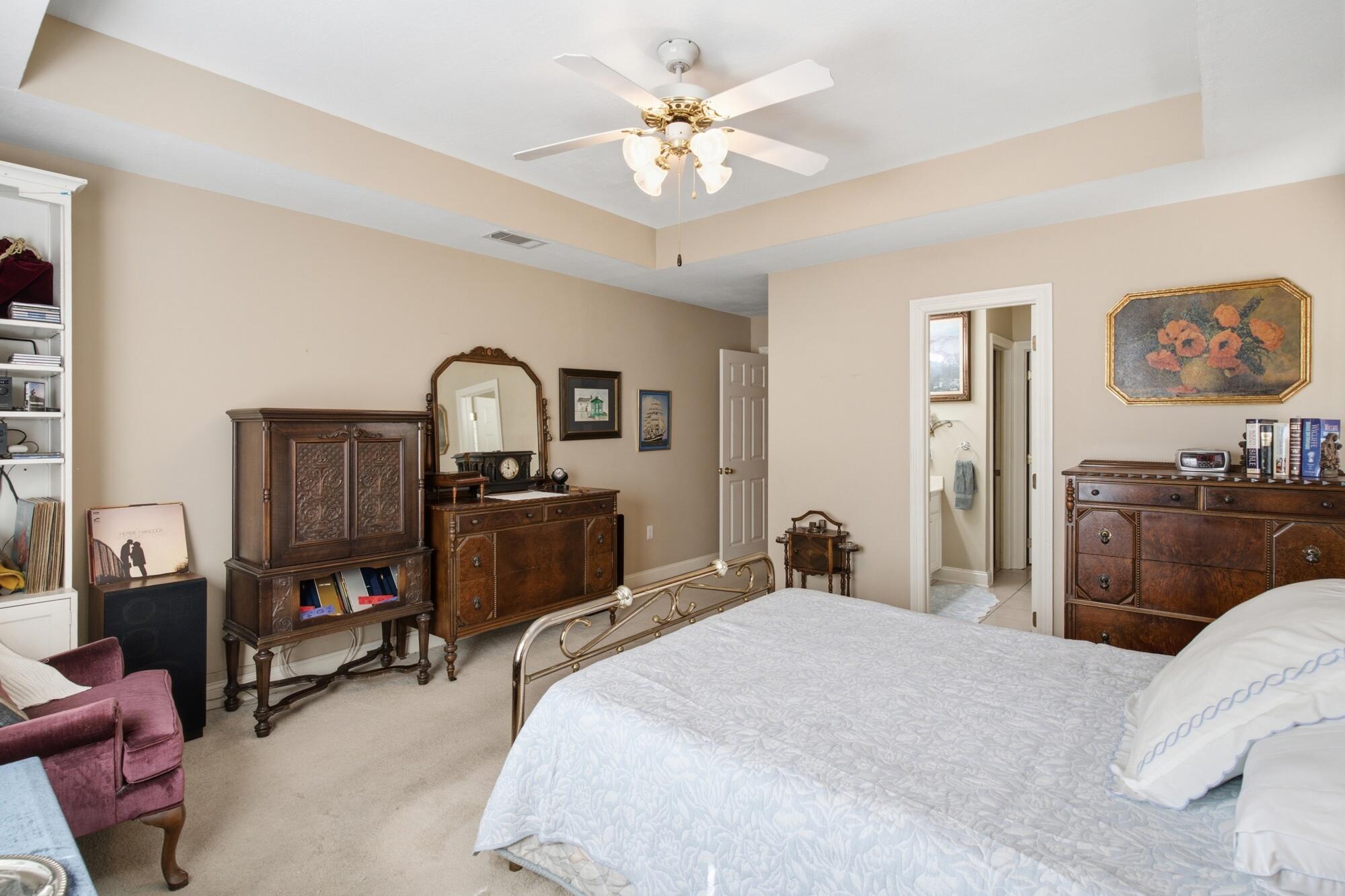 Bedroom with a large bed, ornate dark wood furniture, and an adjoining bathroom doorway.