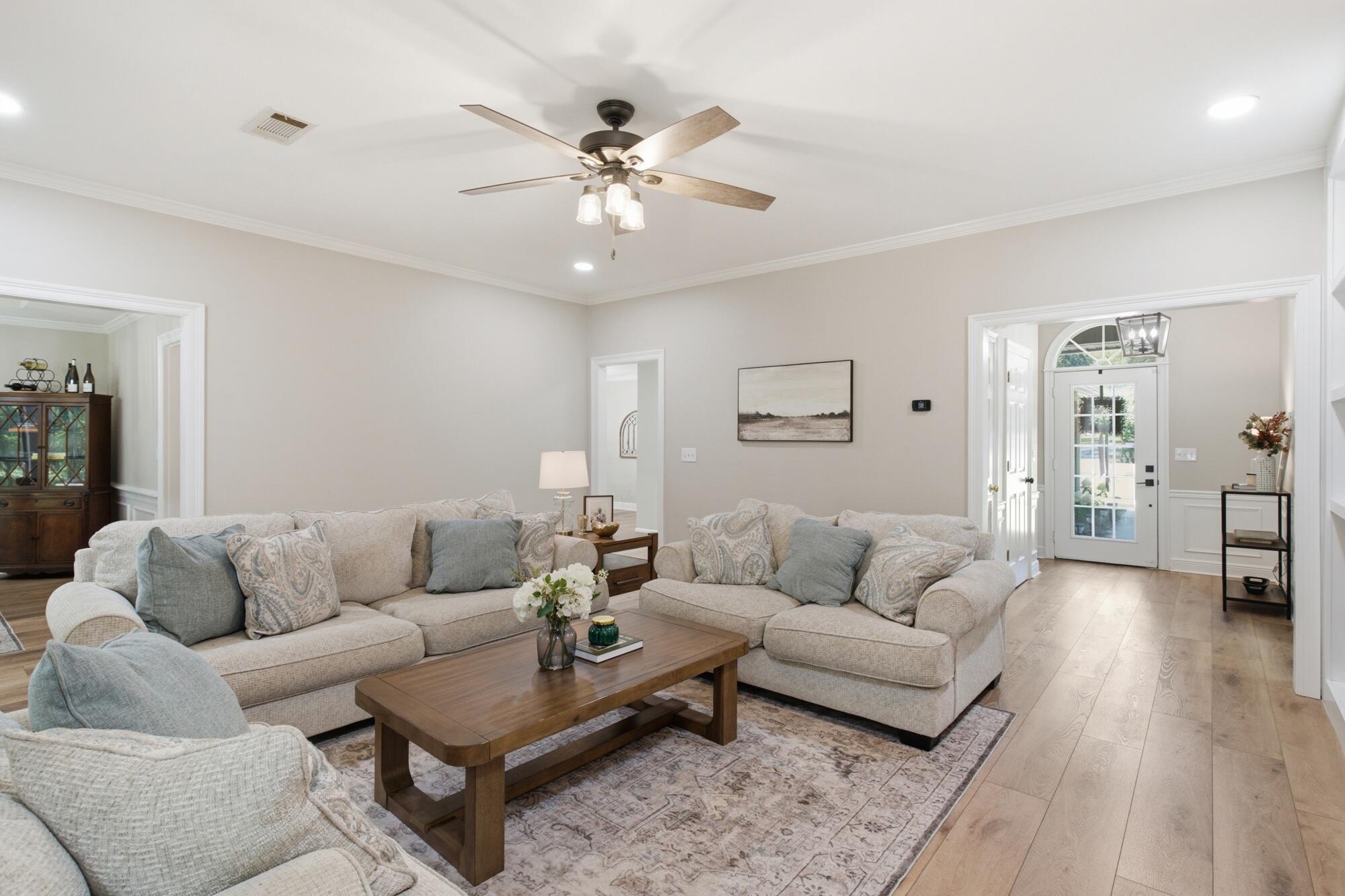 Furnished living room with neutral sofas, a wood coffee table, and a glass-paneled front door.