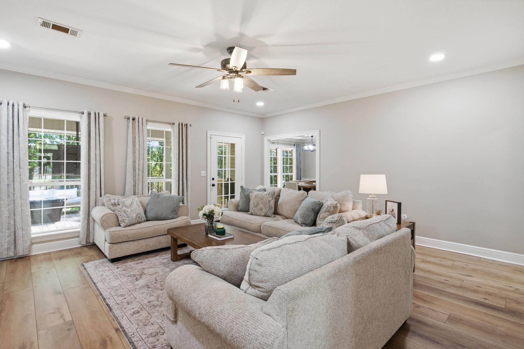 Living room with beige sofas, a wooden coffee table, and large curtained windows.