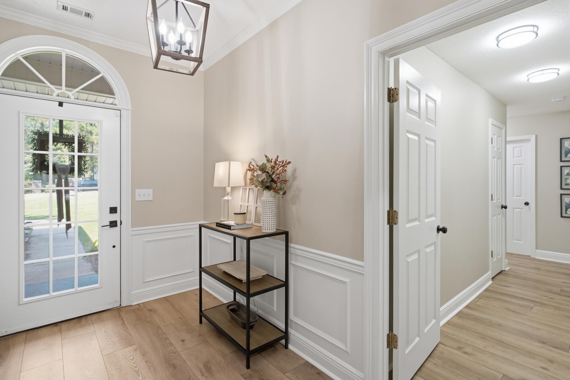 Entry foyer with an arched glass-paneled front door, wood flooring, and a decorated console table.