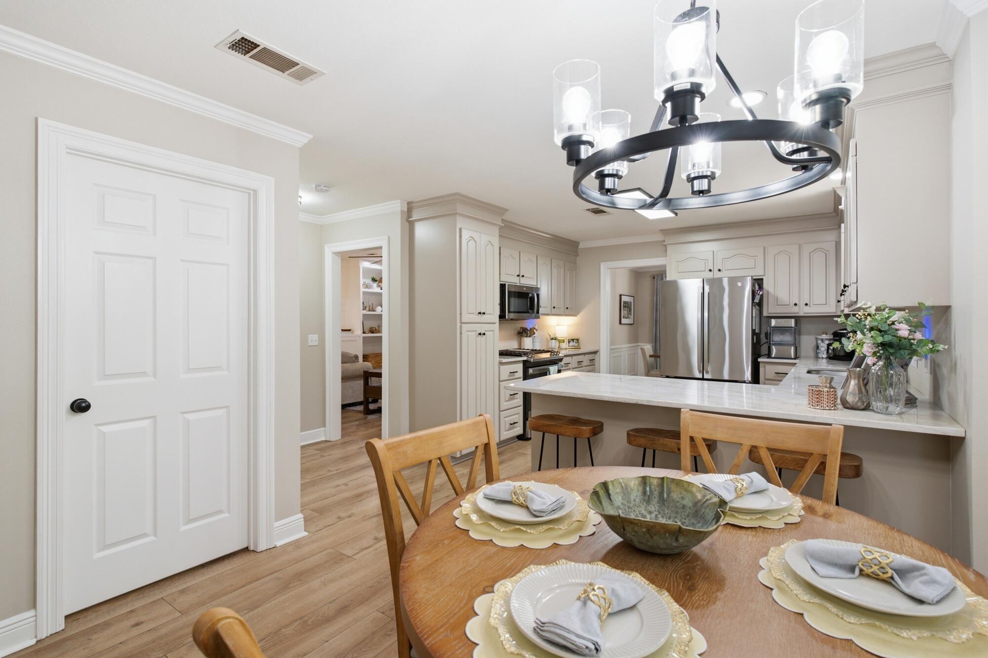 Kitchen and dining area with white cabinets, stainless appliances, island seating, and a set wooden table.