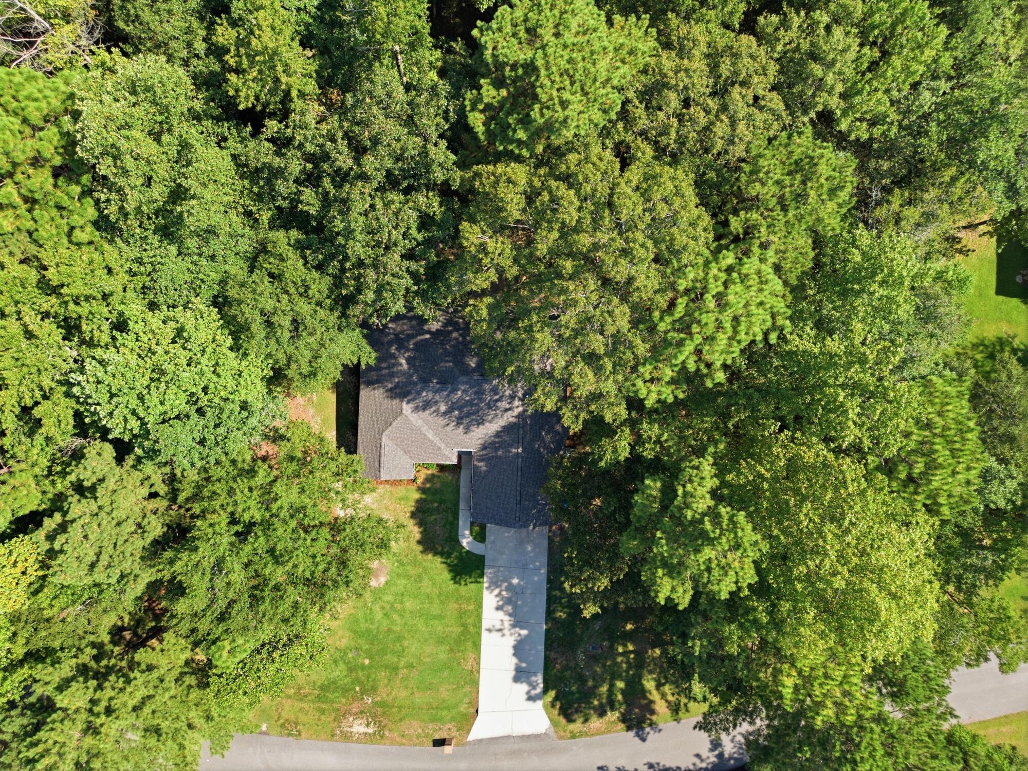 Aerial view of a house and long driveway surrounded by dense trees.